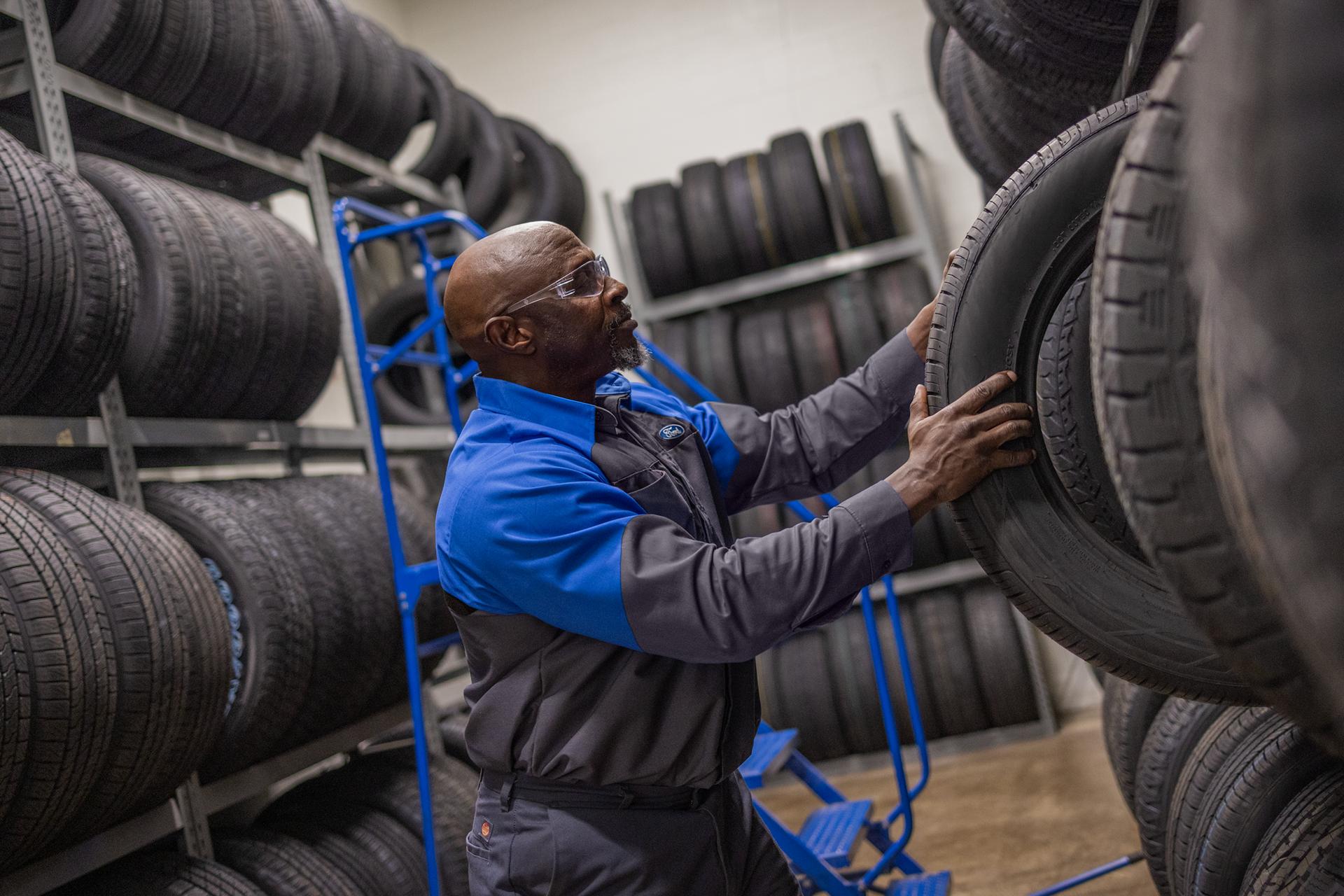 A Ford Service technician pulling a tire from the tire stock