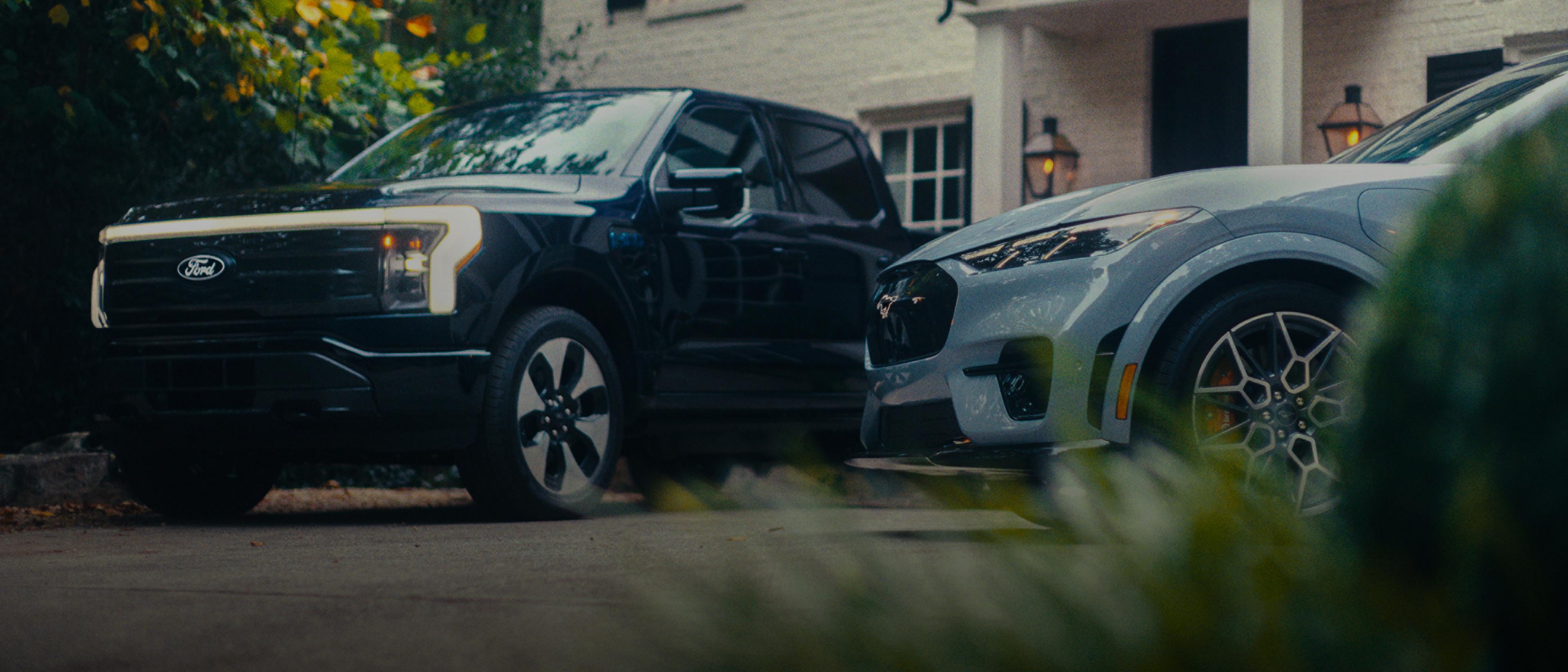Ford F-150 Lightning and Ford Mustang Mach-E parked outside of a white brick home