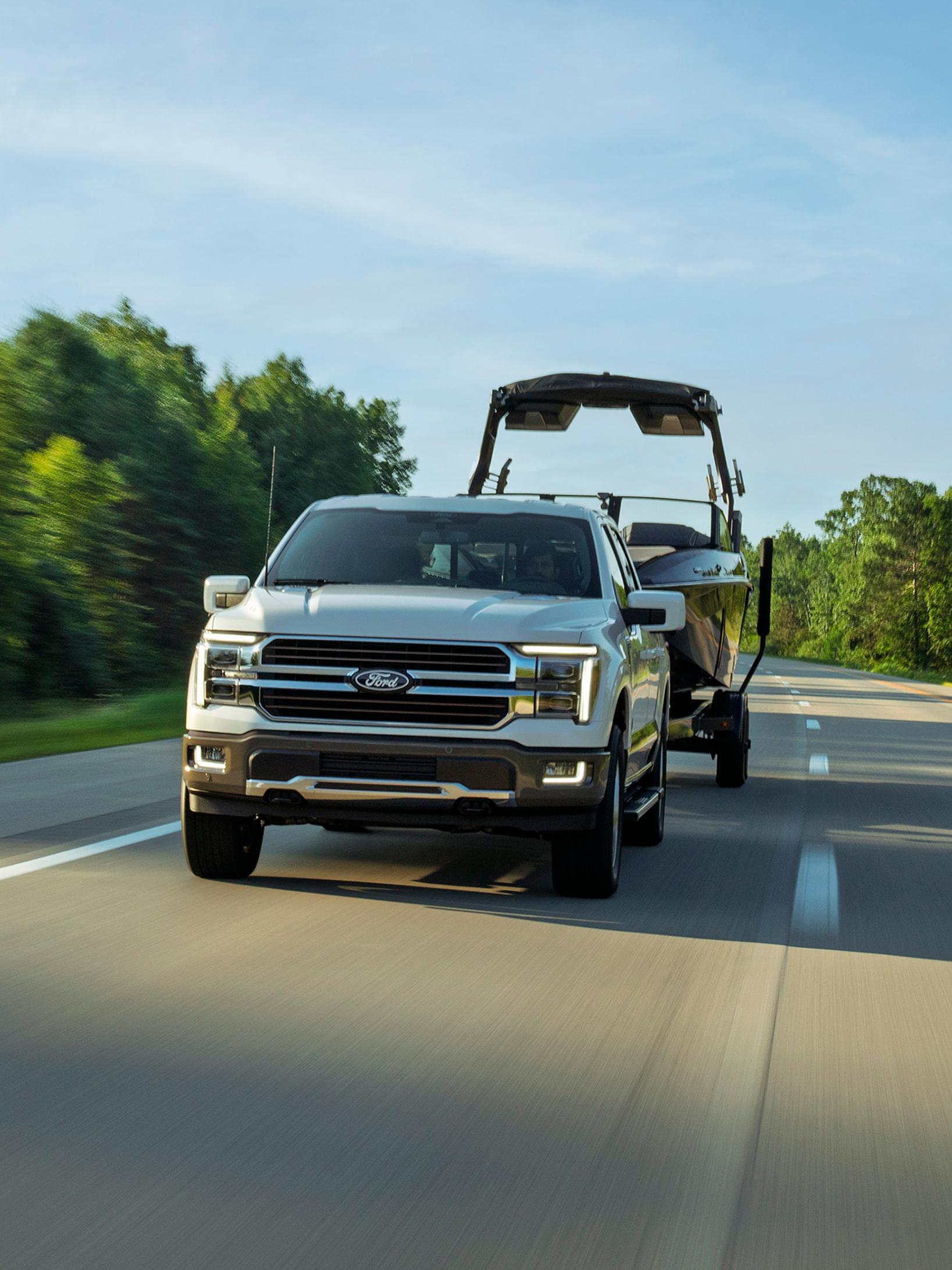 2027 Ford F-150® Lariat® pickup pulling a boat on a highway