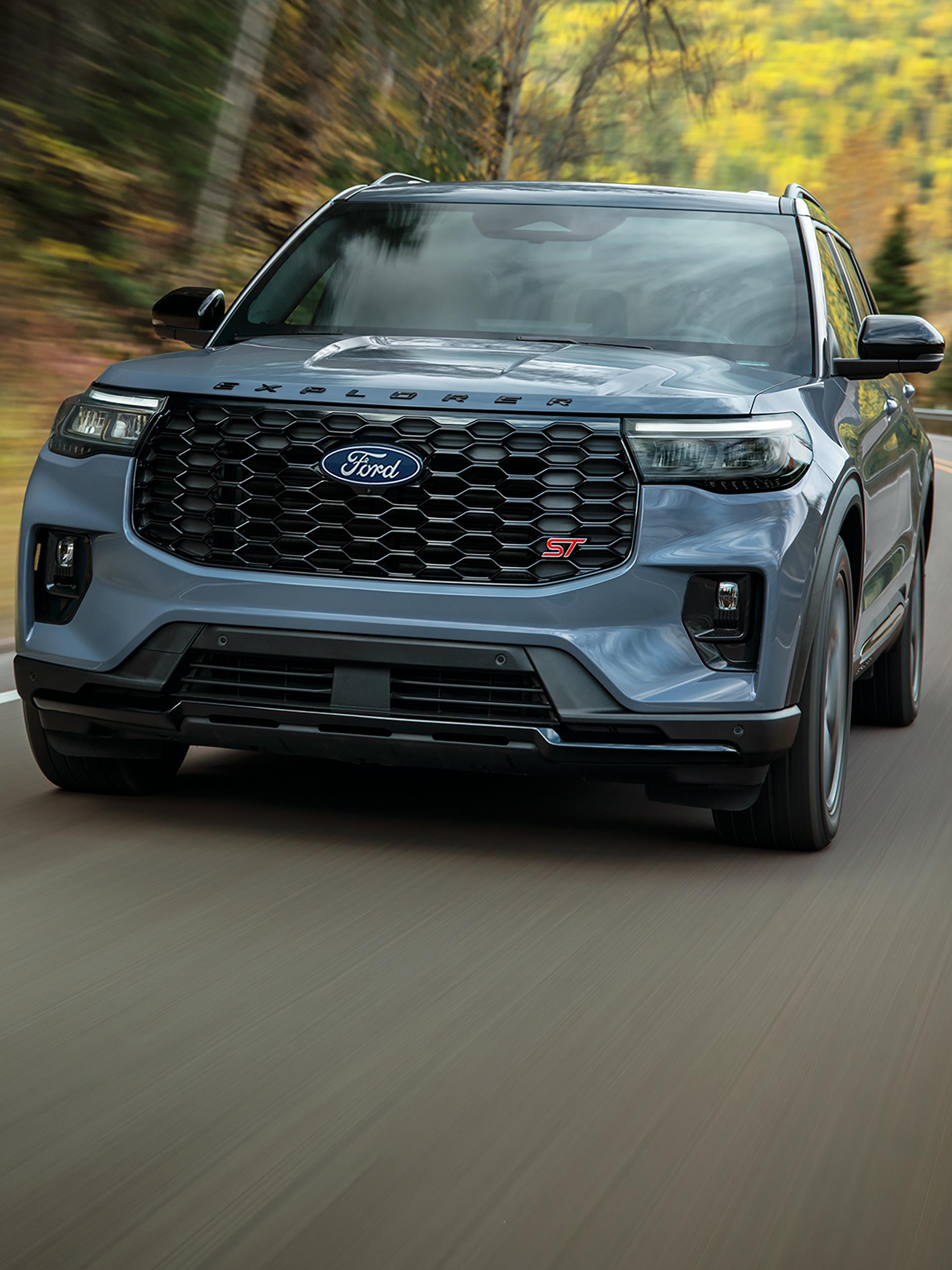 Una SUV Ford Explorer® ST 2027 andando por una carretera boscosa