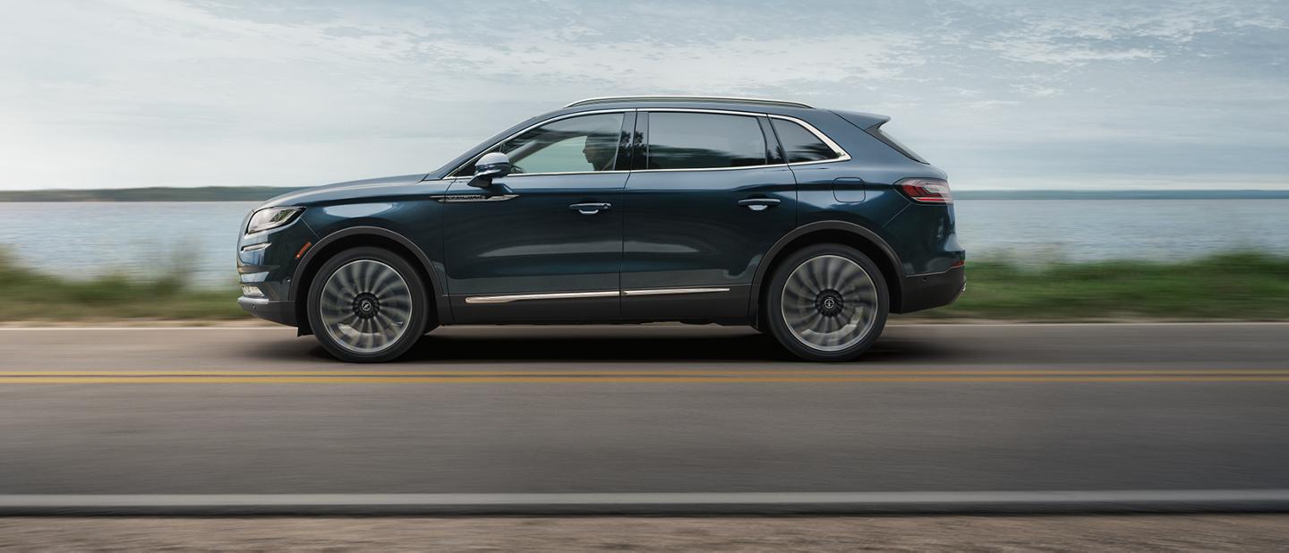 A Lincoln Nautilus® SUV drives down a lakeside country road