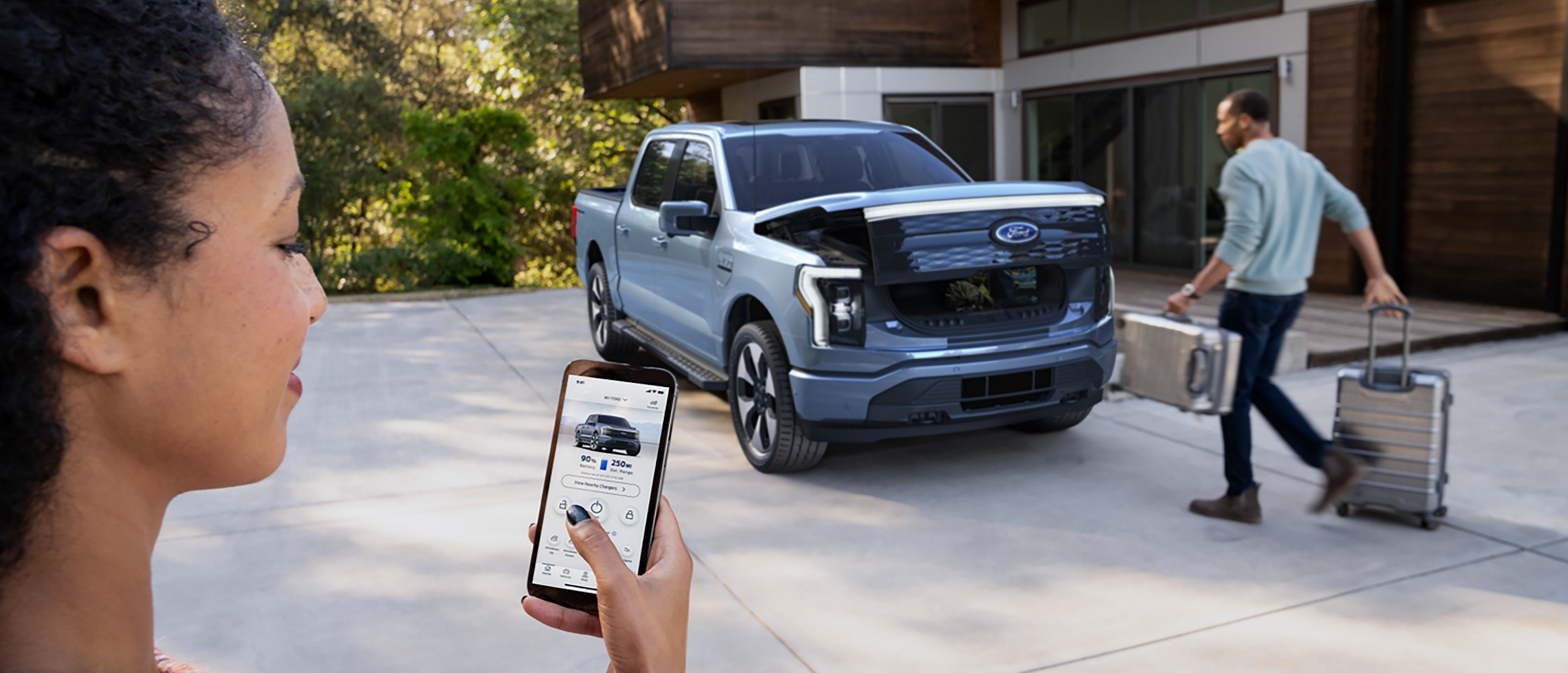 A couple get ready for a trip, loading luggage into the frunk of their Ford F-150® Lightning® truck