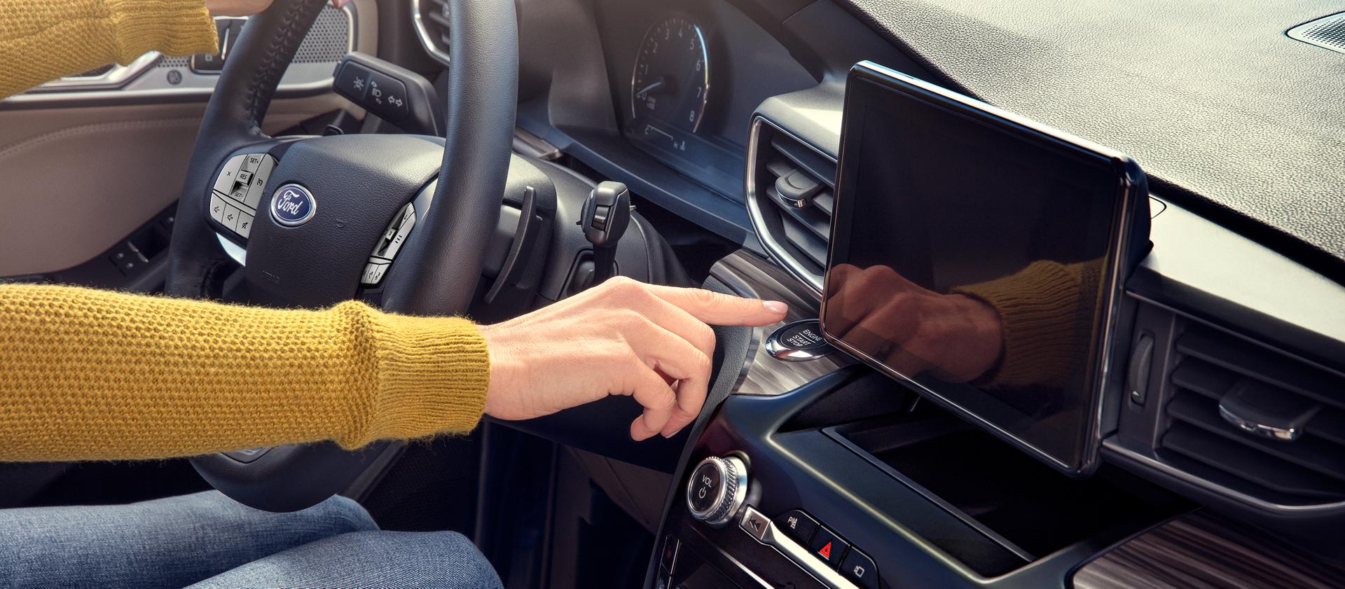 A driver presses the start engine button in their Ford vehicle