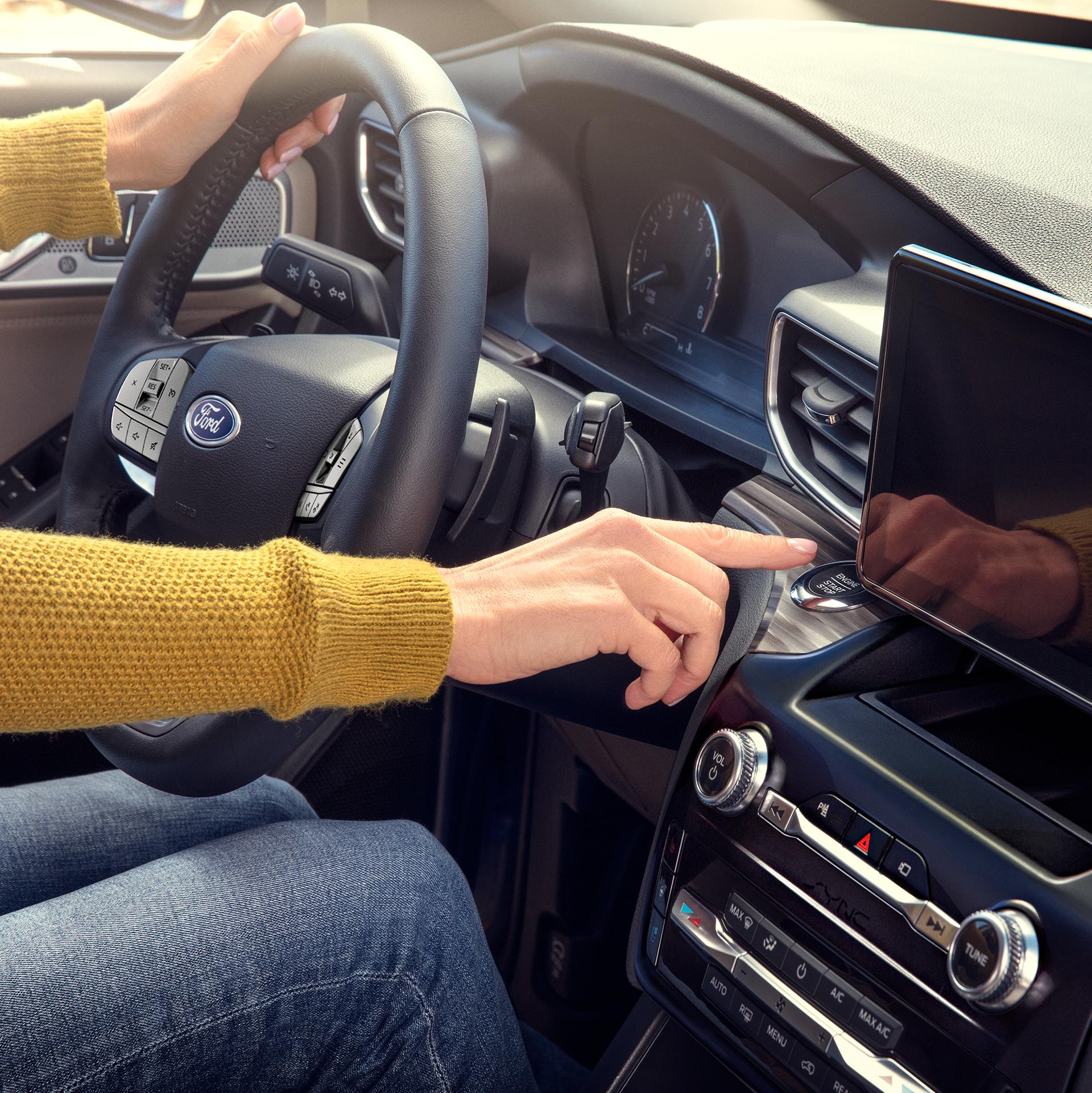 A driver presses the start engine button in their Ford vehicle
