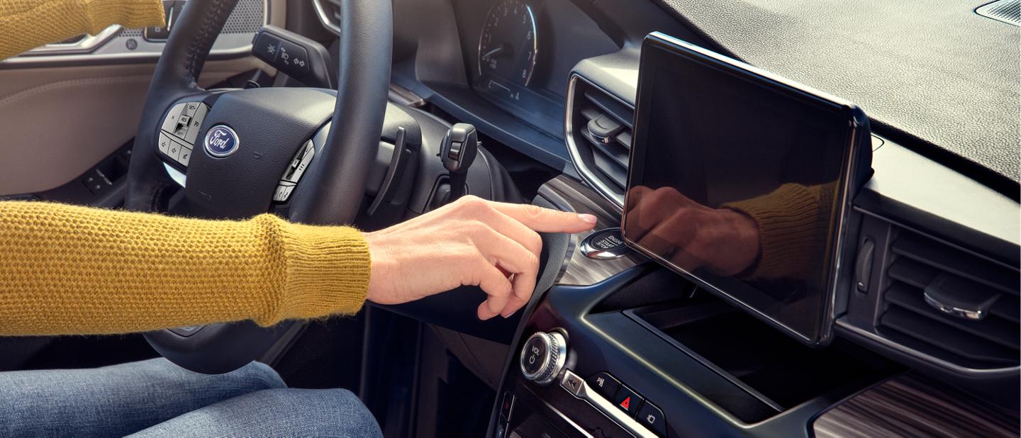 A driver presses the start engine button in their Ford vehicle