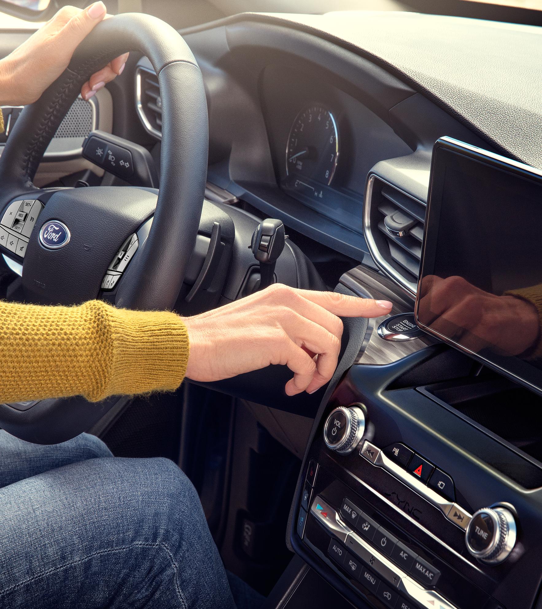 A driver presses the start engine button in their Ford vehicle
