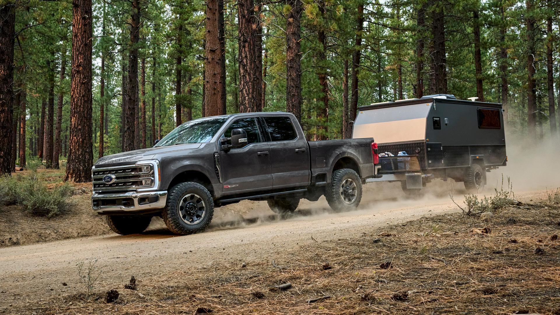 2026 Ford Super Duty® F-250® with the Tremor® Off-Road Package pulling a trailer on a dirt road in the woods