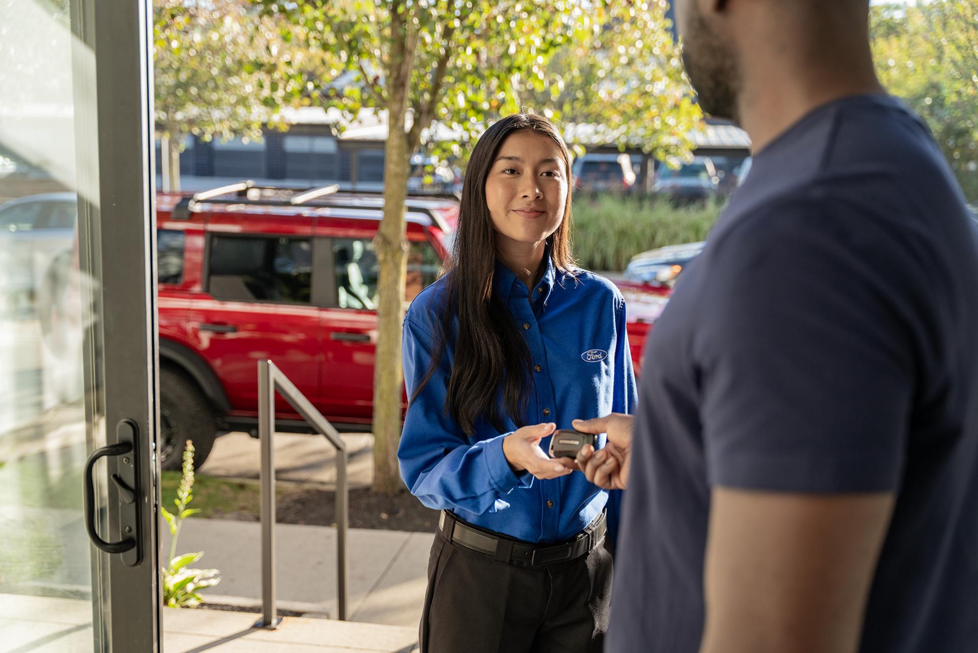 A Ford owner hands keys over to a Ford Pickup & Delivery representative