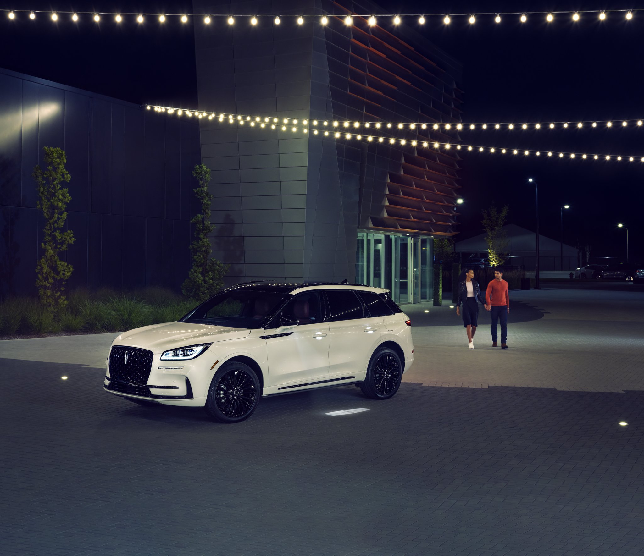 Un couple s’approche d’un VUS Lincoln Corsair 2026 alors que l’éclairage Lincoln Embrace guide le chemin