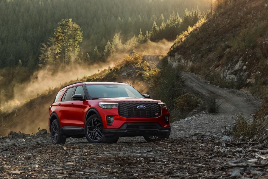A Ford Explorer is parked alongside a dirt road in a hilly, scenic area.