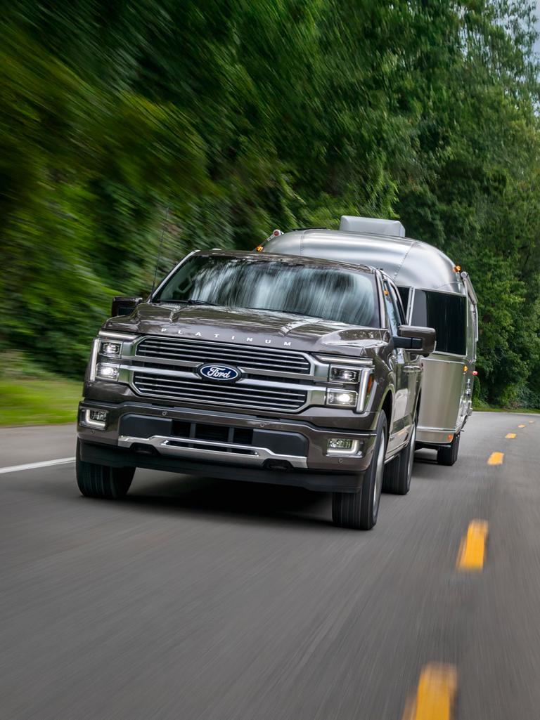 2025 Ford F-150® Platinum® truck in Marsh Gray pulling a camper