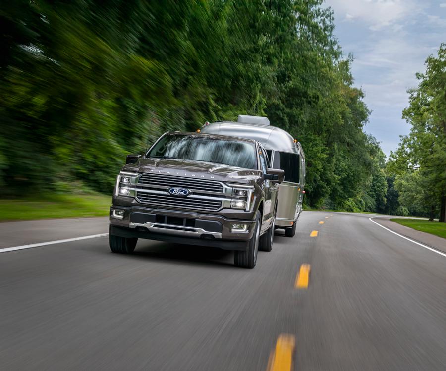 2025 Ford F-150® Platinum® truck in Marsh Gray pulling a camper