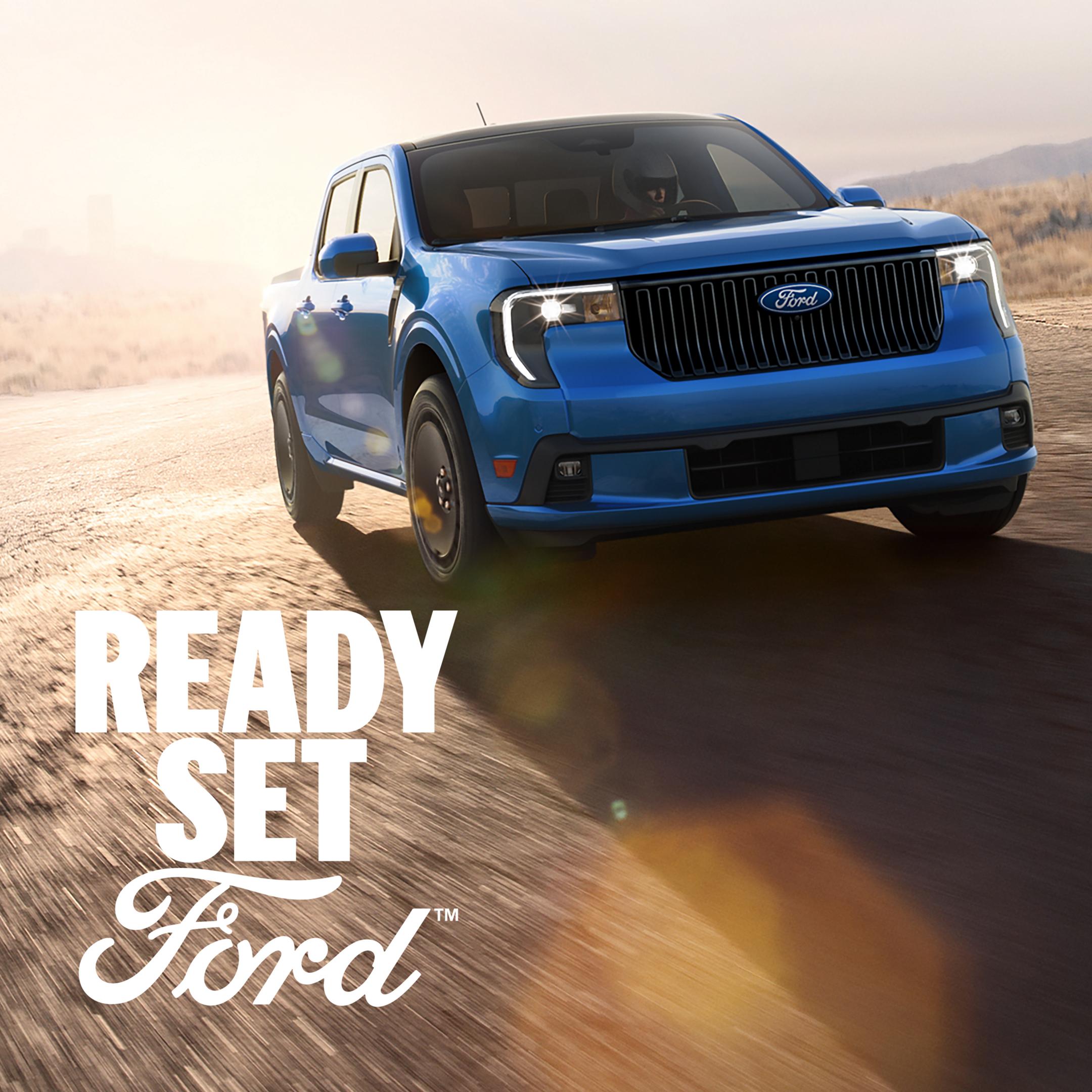 2026 Ford Maverick Lobo™ model in Velocity Blue Metallic being driven on a closed course with a city scape in the background