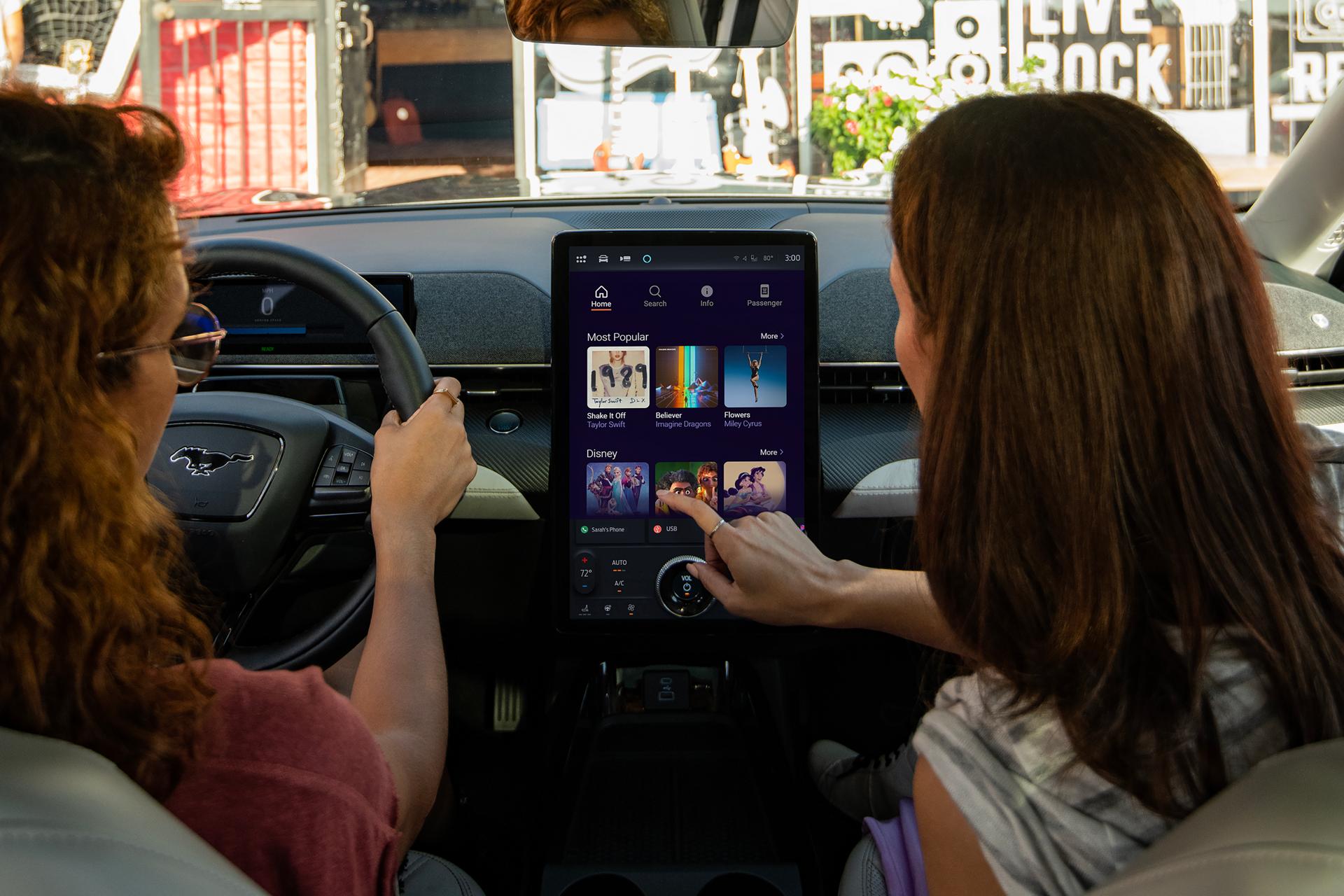 Two women in a 2026 Ford Mustang Mach-E® browsing karaoke options with available Connectivity Package