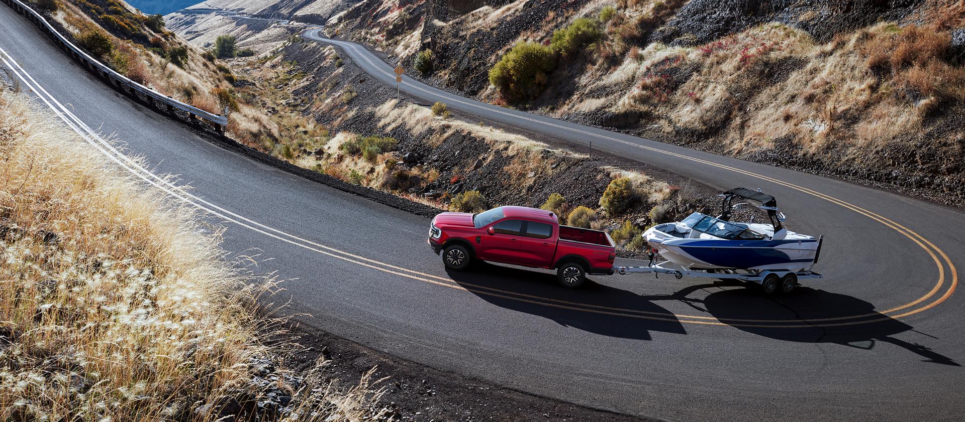 A 2026 Ford Ranger® truck pulling a speed boat on a winding, mountainous highway