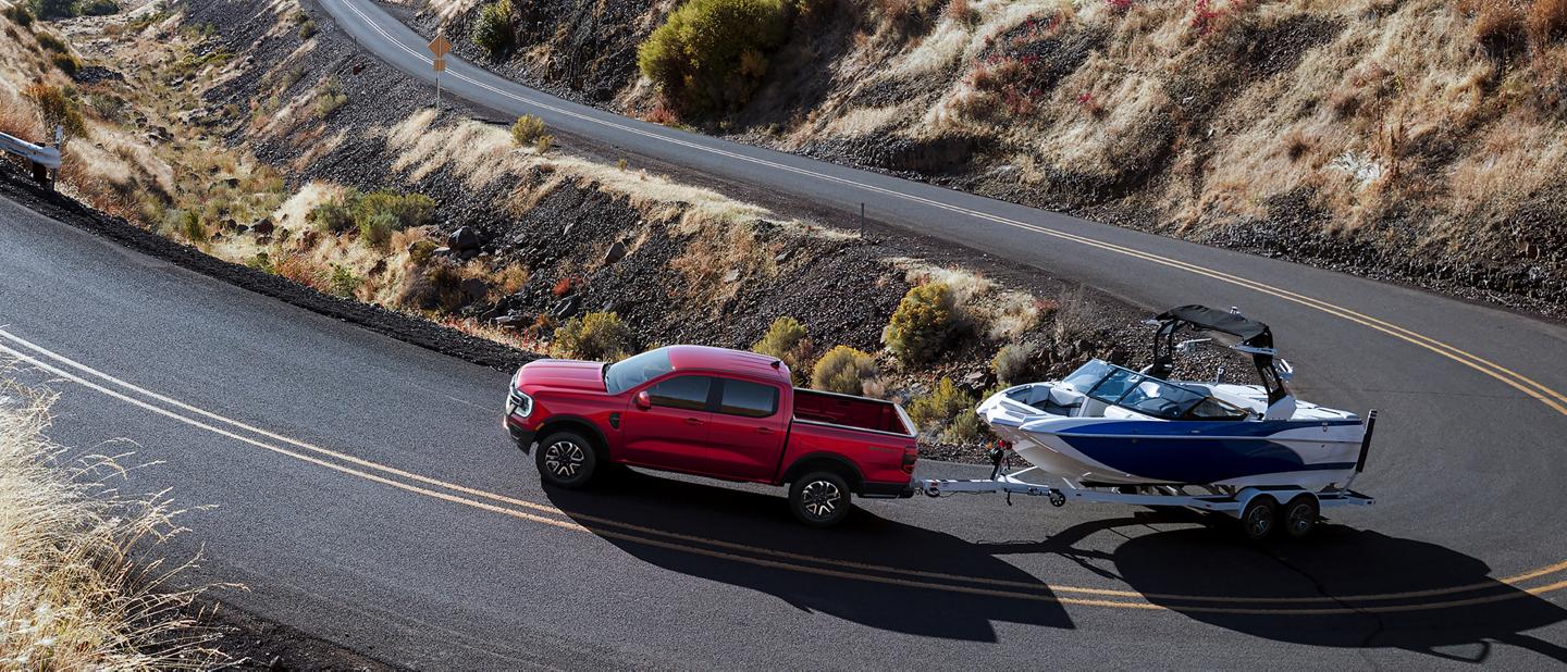 A 2026 Ford Ranger® truck pulling a speed boat on a winding, mountainous highway