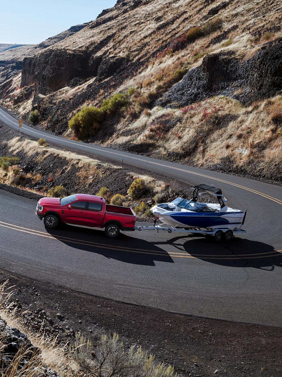 A 2026 Ford Ranger® truck pulling a speed boat on a winding, mountainous highway