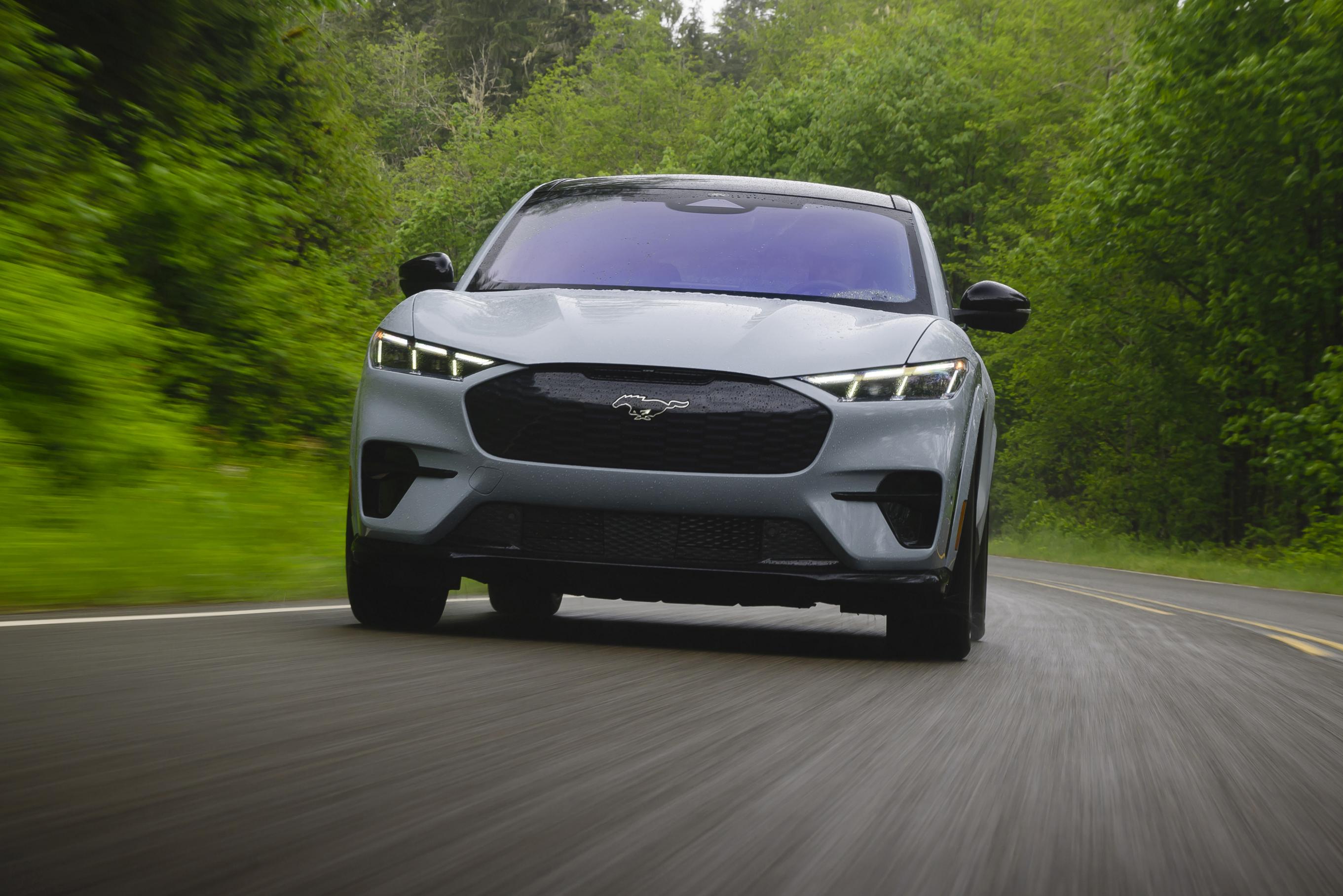 Ford Mustang Mach‑E driving on a forested road