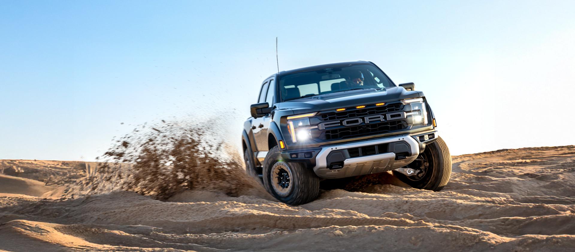 A Ford Raptor driving through sand.