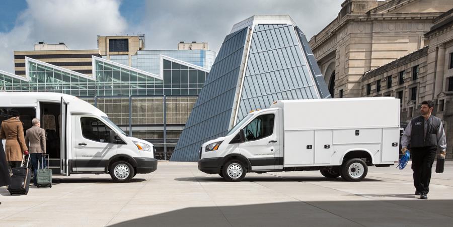 A person walking near a 2025 Ford Transit® model parked in a city carrying work supplies