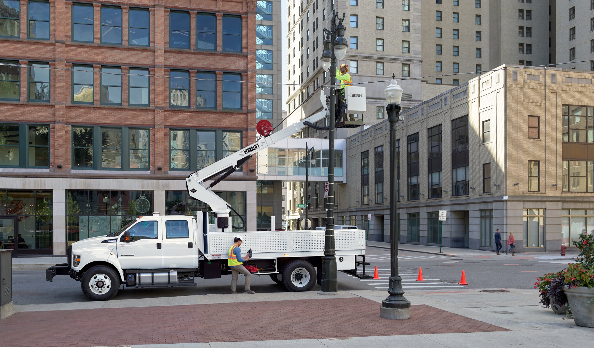 Travailleur réparant un lampadaire à l’intérieur d’une nacelle élévatrice aménagée sur le Ford F-750 2025 à cabine 6 places couleur blanc Oxford