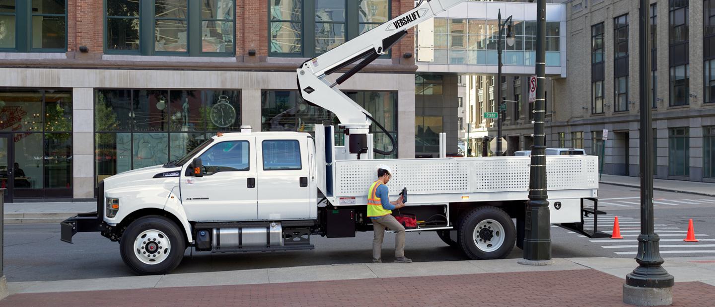 Travailleurs remplaçant un lampadaire en ville avec un Ford F-750 2025 à cabine six places en blanc Oxford avec aménagement de nacelle élévatrice