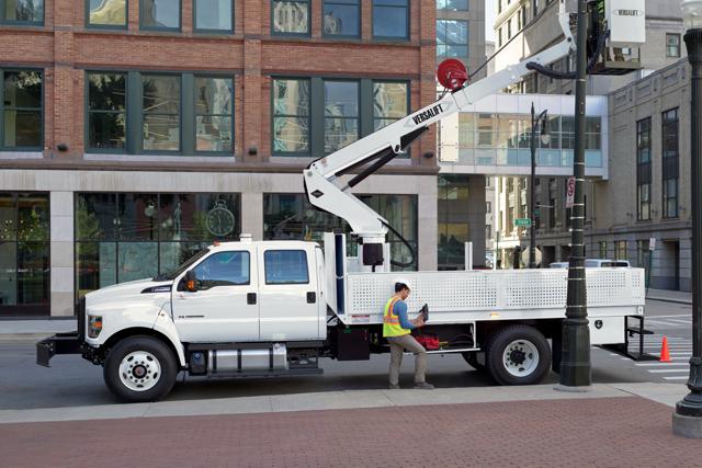 Travailleurs remplaçant un lampadaire en ville avec un Ford F-750 2025 à cabine six places en blanc Oxford avec aménagement de nacelle élévatrice