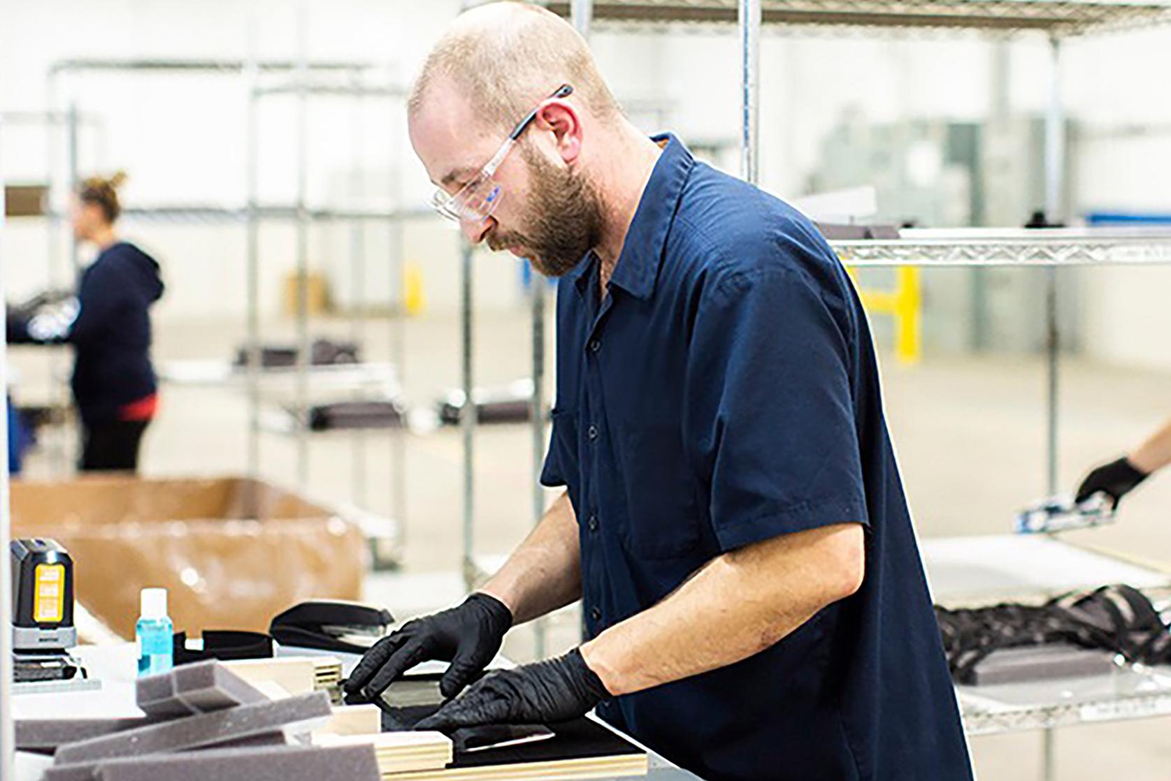 An employee assembles a face shield