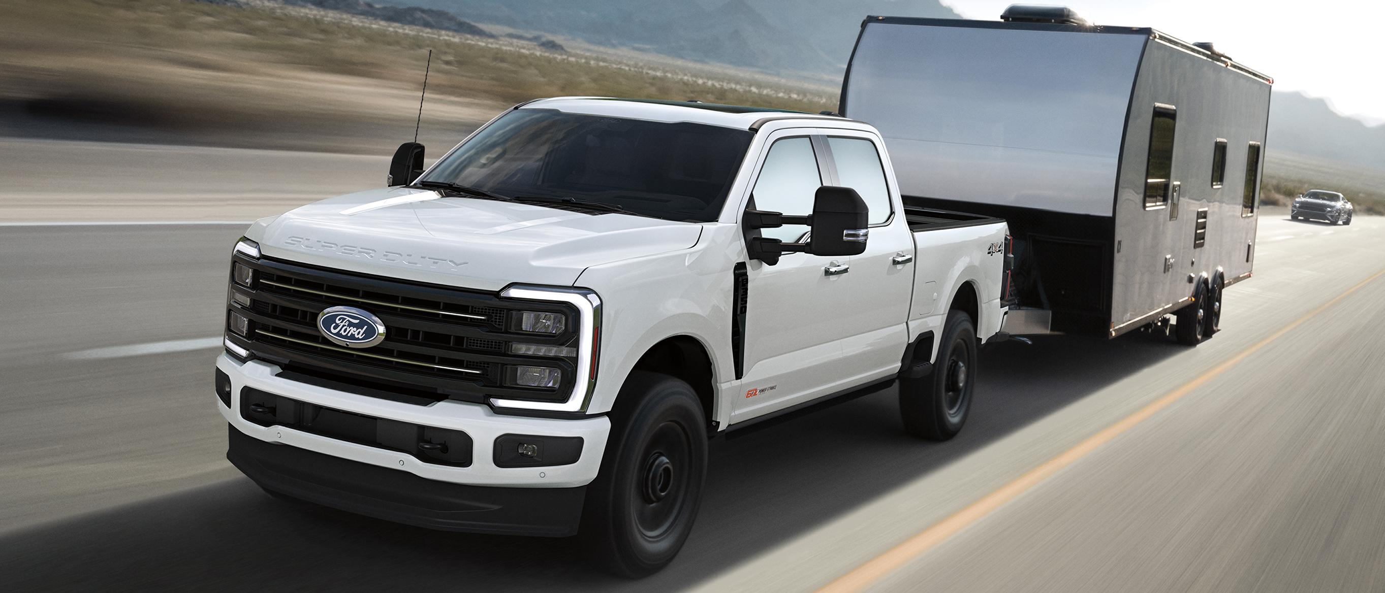 A 2027 Ford Super Duty® F-350® Platinum® model pulling a large camper on a paved road   