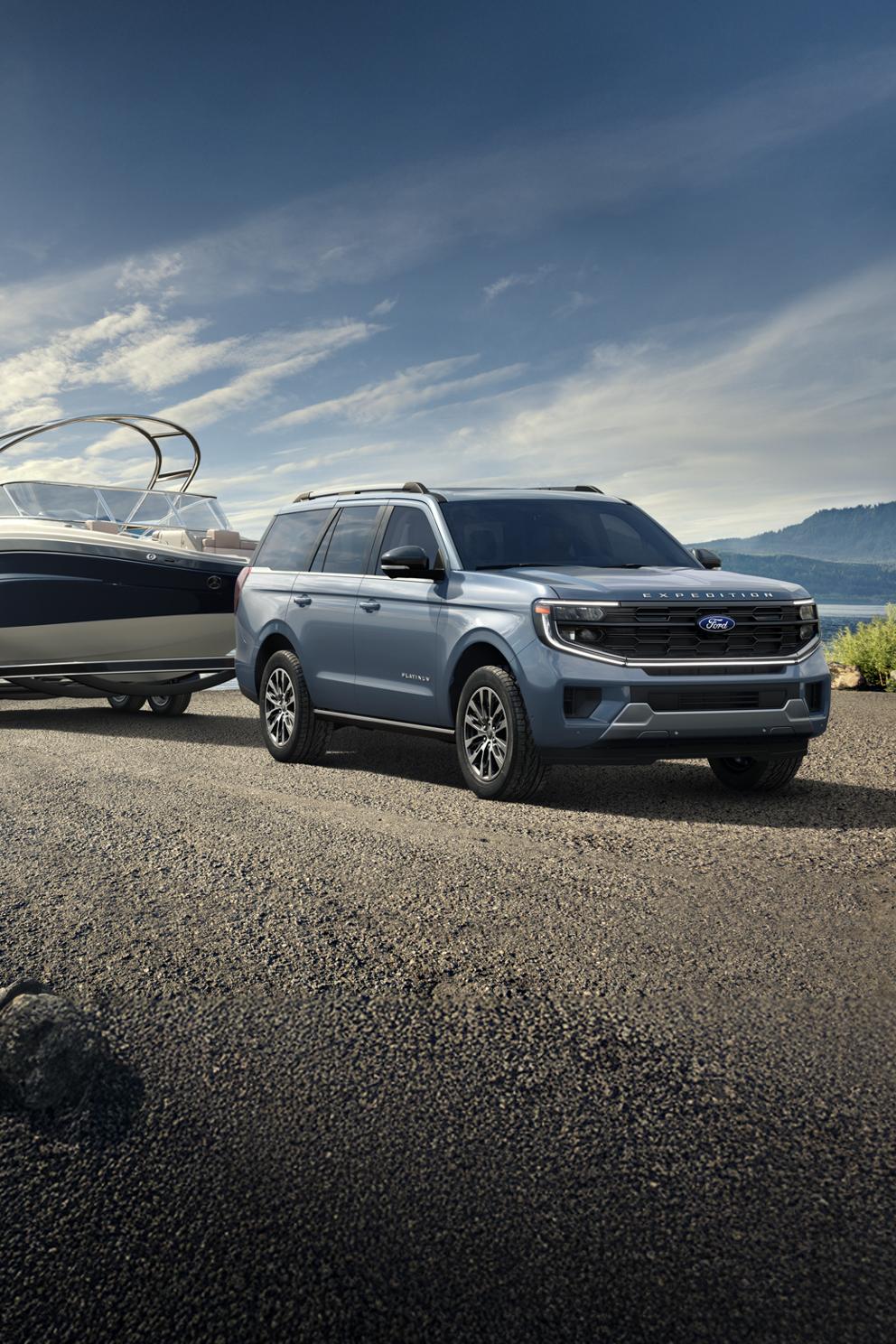 A blue 2025 Ford Expedition parked on gravel by a lake with a boat in tow