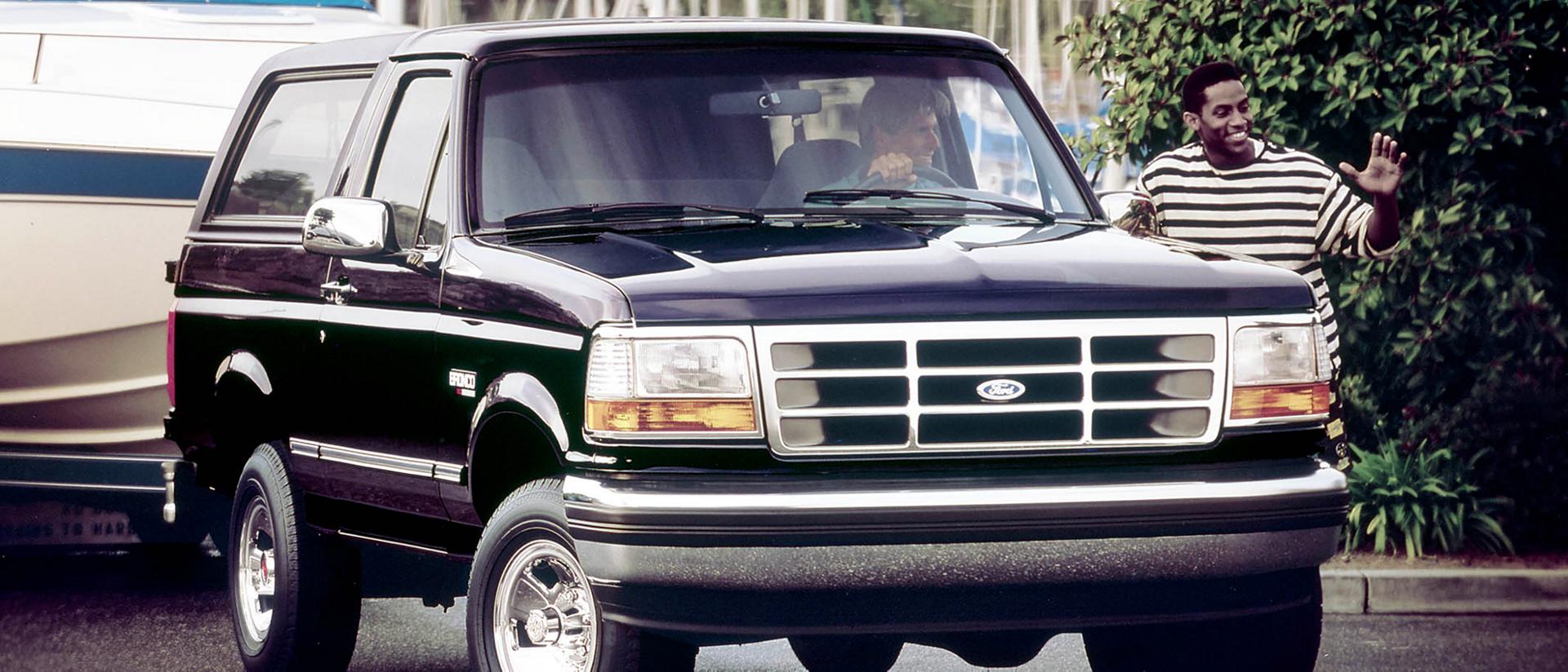 A vintage black 1994 Ford Bronco® model parked while set to tow a boat