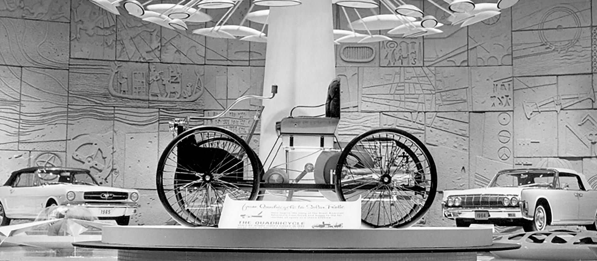 A black and white photo of a Quadricycle on a display platform
