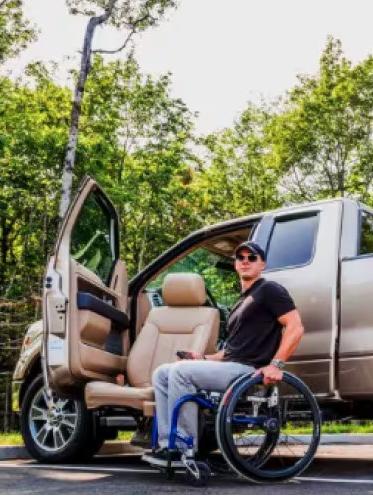 Person in a wheelchair beside a Ford truck