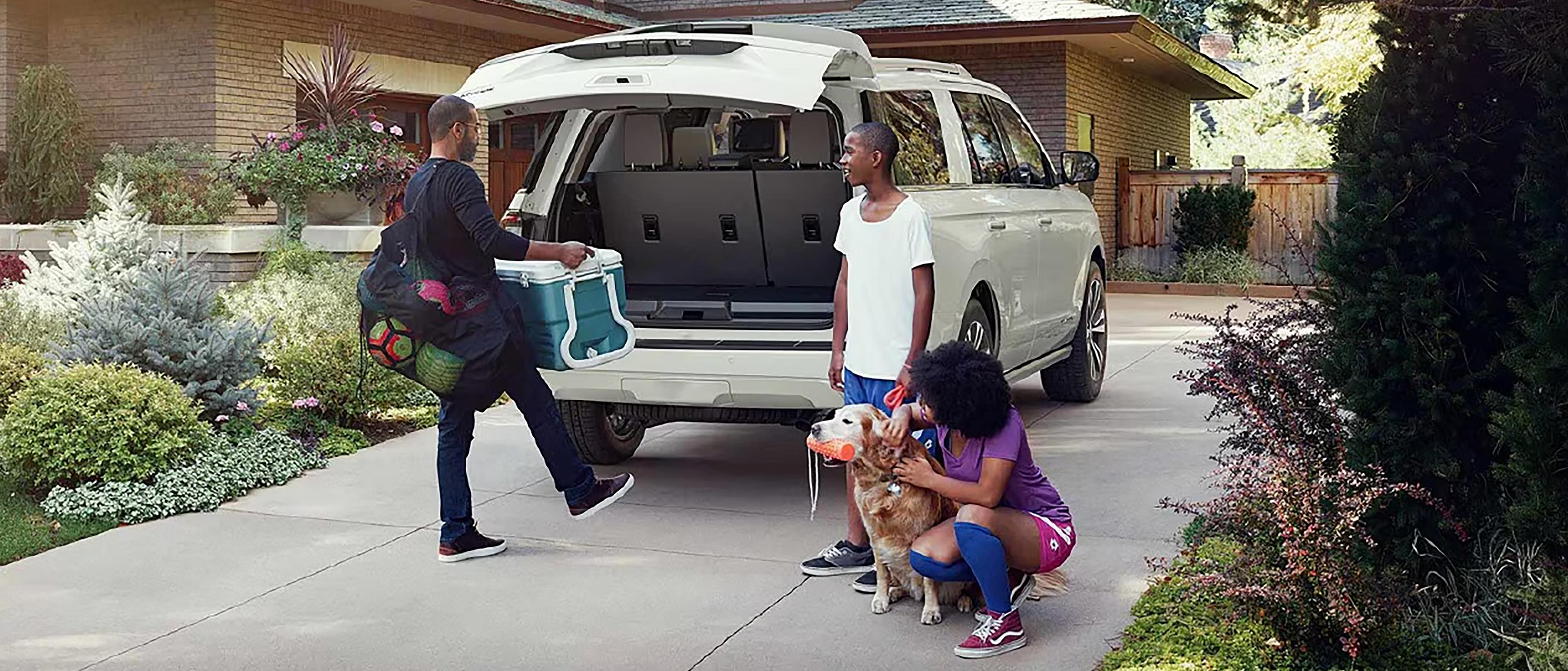 A family carries gear to the open liftgate of their Ford Expedition® SUV parked in the driveway