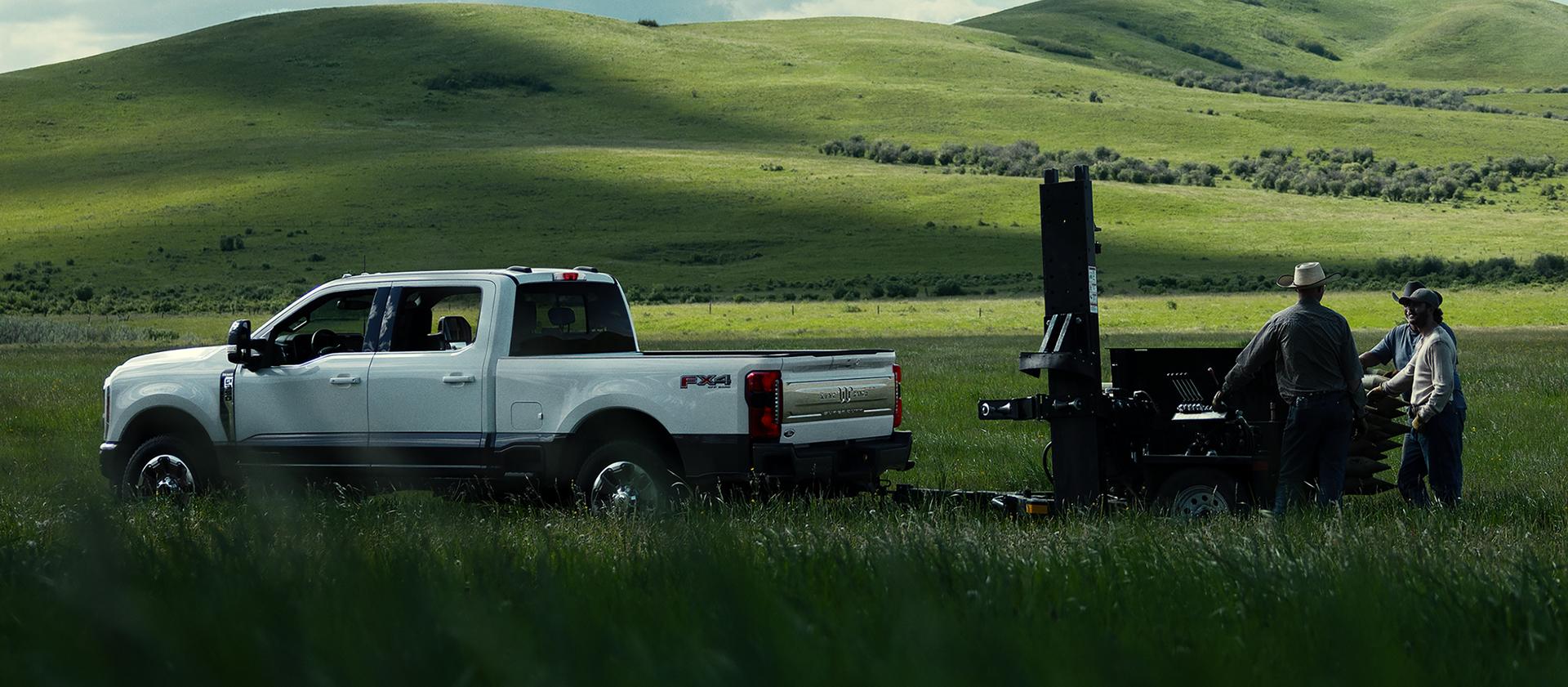2027 Ford Super Duty® F-350® King Ranch® model towing a trailer through a grassy field