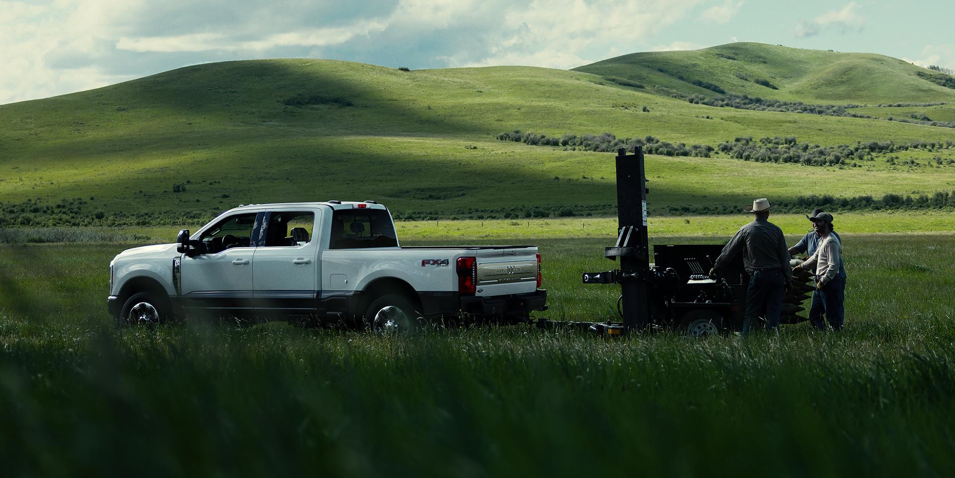 2027 Ford Super Duty® F-350® King Ranch® model towing a trailer through a grassy field