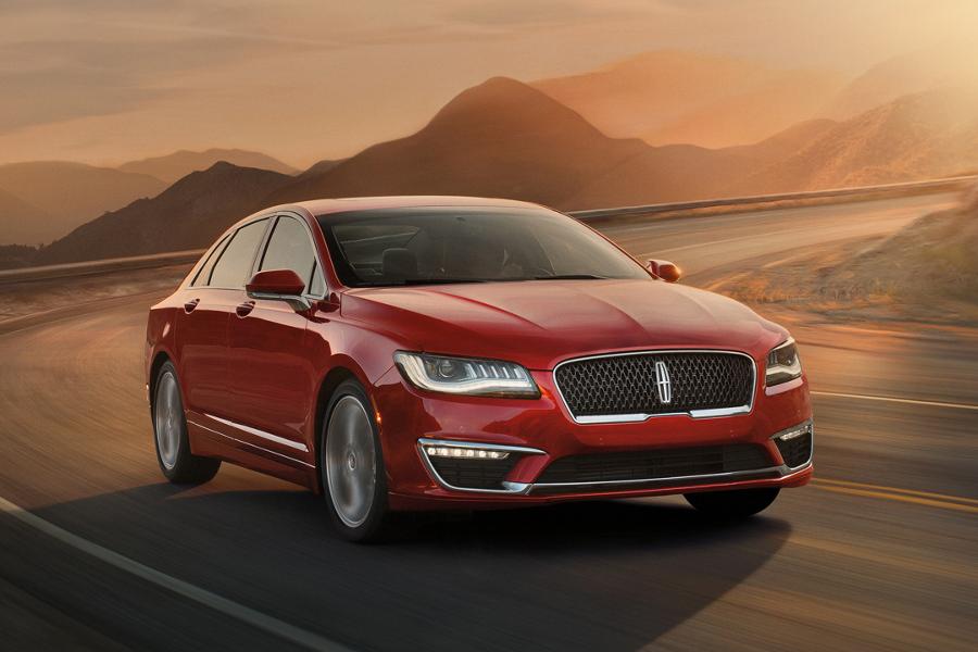 A Lincoln MKZ is being driven along a curved mountain road in the orange glow of dawn light