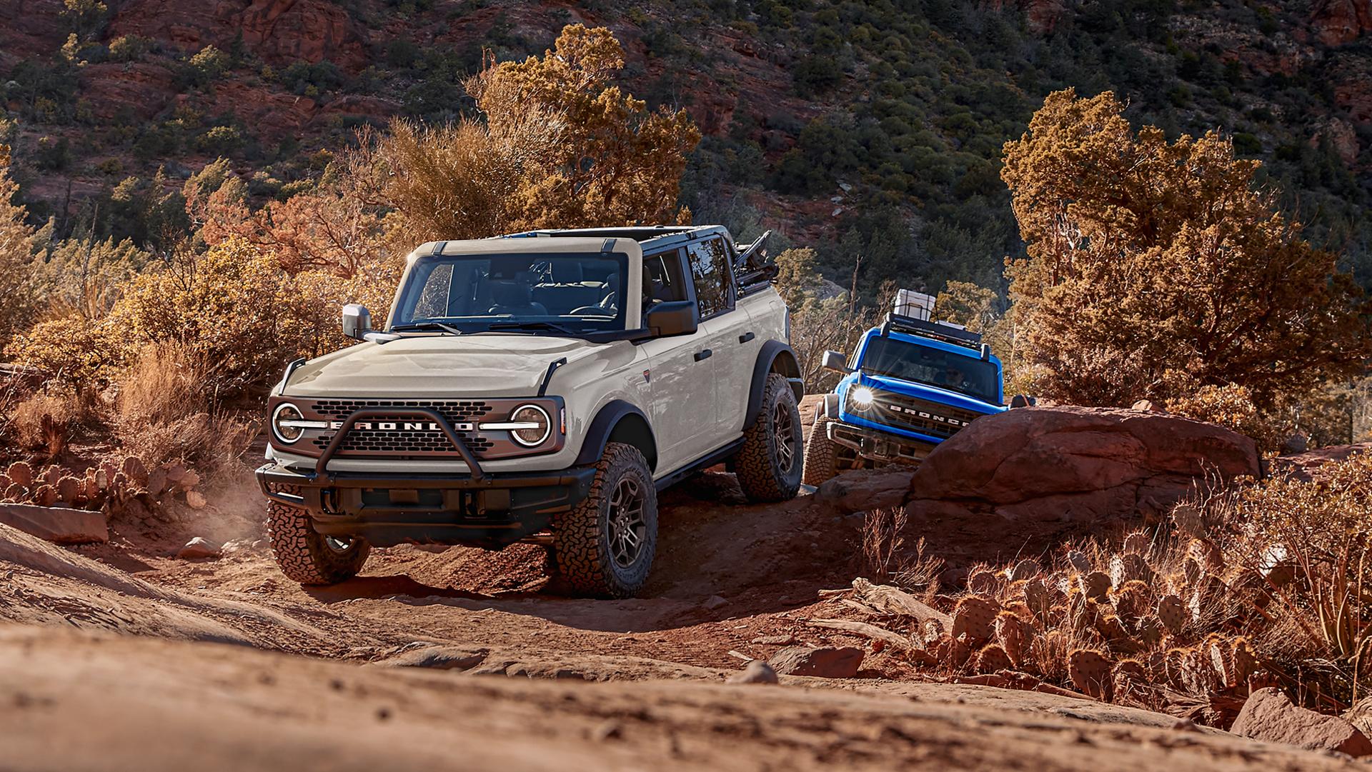 Two 2026 Ford Bronco® SUVs being driven on a scrubby dirt trail
