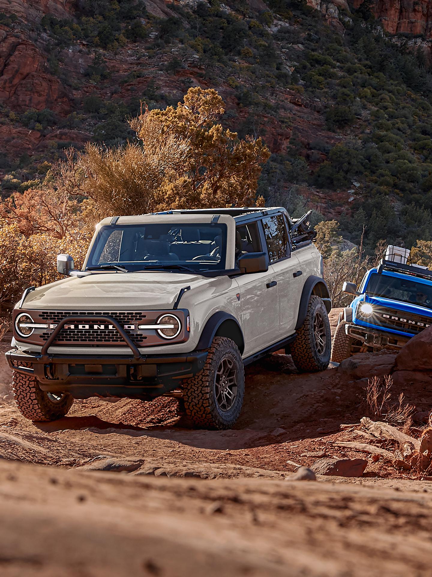 Two 2026 Ford Bronco® SUVs being driven out of a canyon trail