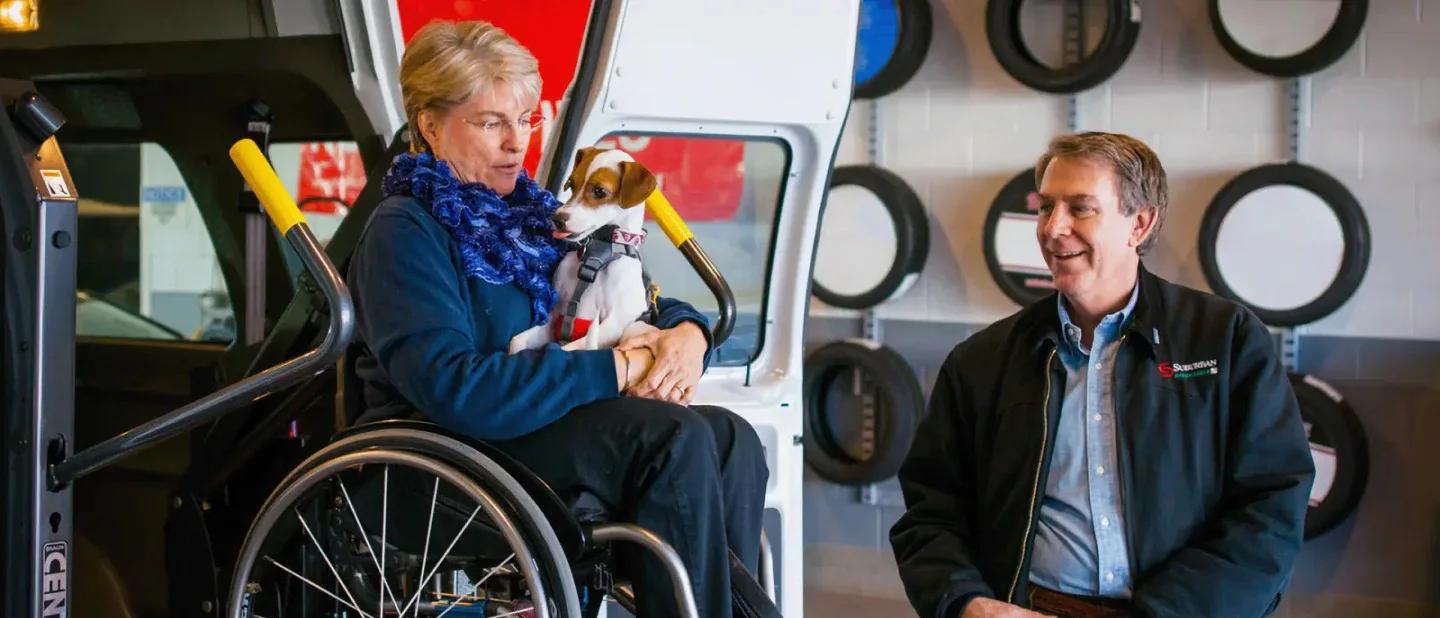 Woman in wheelchair holding puppy on a Ford Transit® van lift