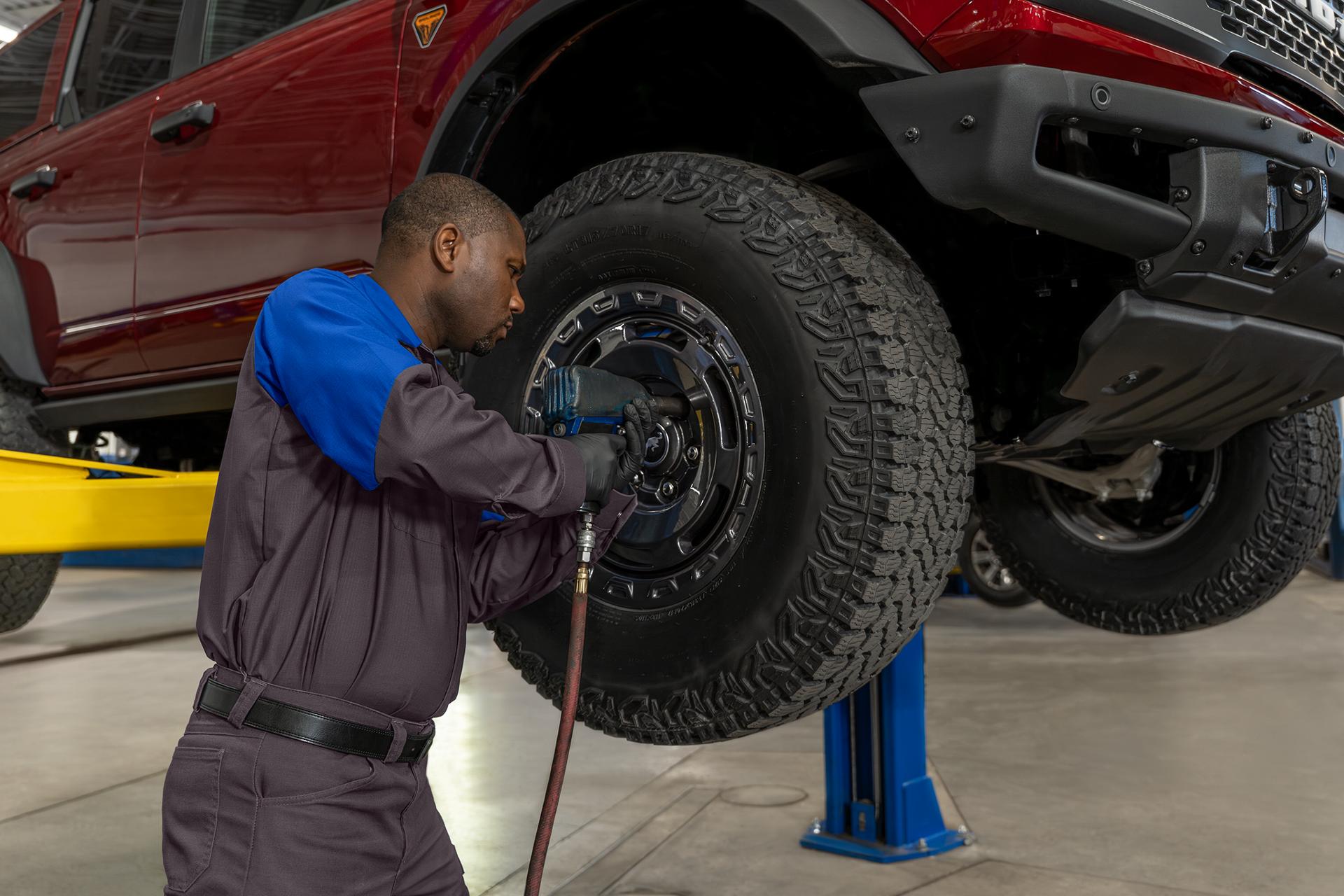 A Ford Service technician puts a new tire on a Ford vehicle