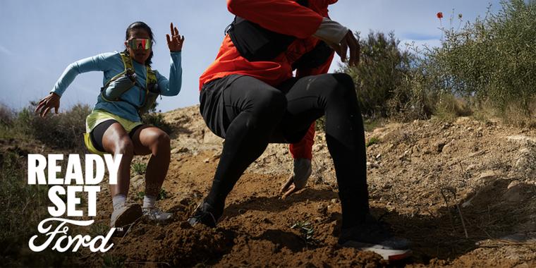 Two people running on a mountain trail