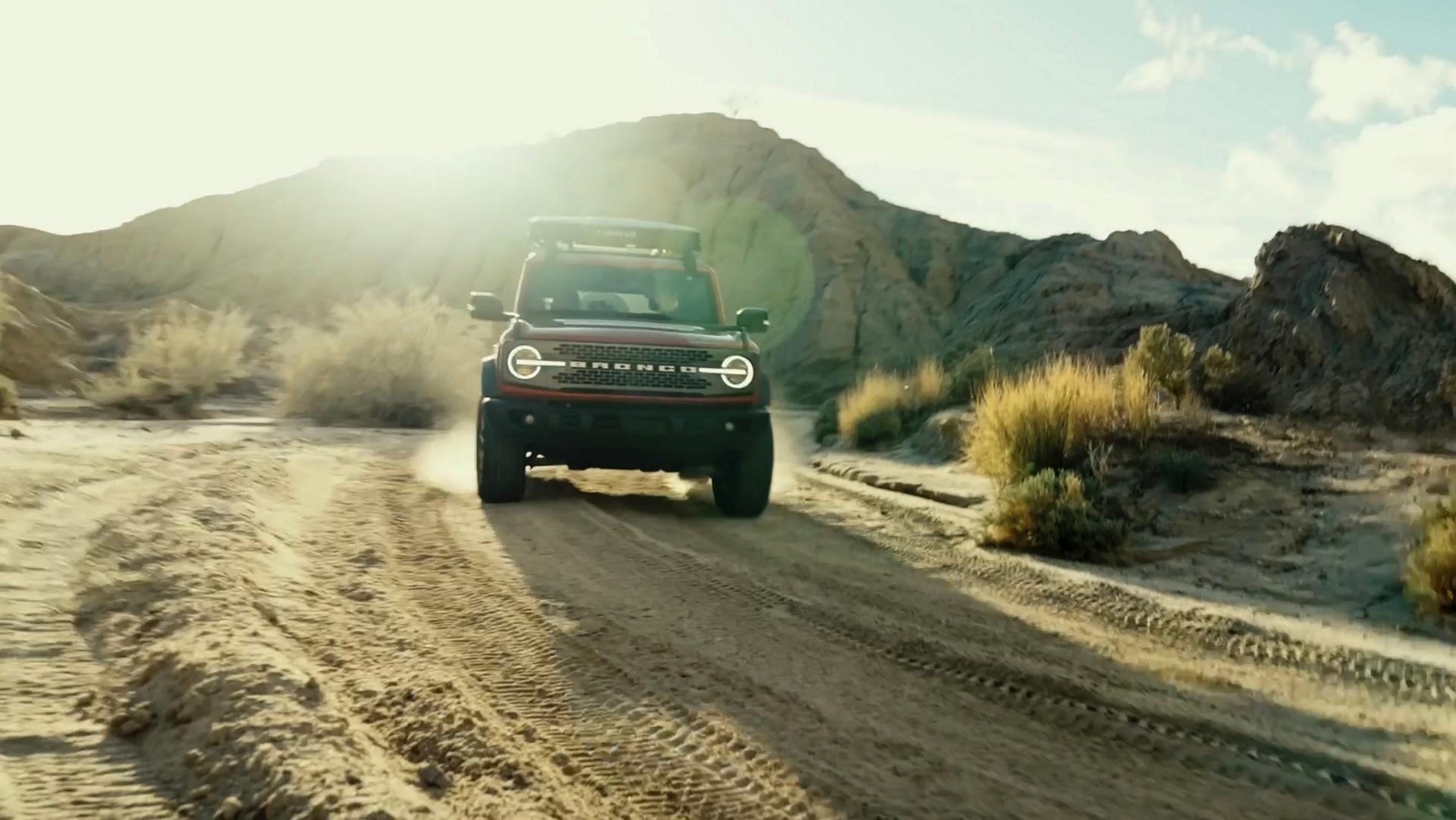 A 2026 Ford Bronco® SUV being driven on a dirt trail through a stark, dusty landscape