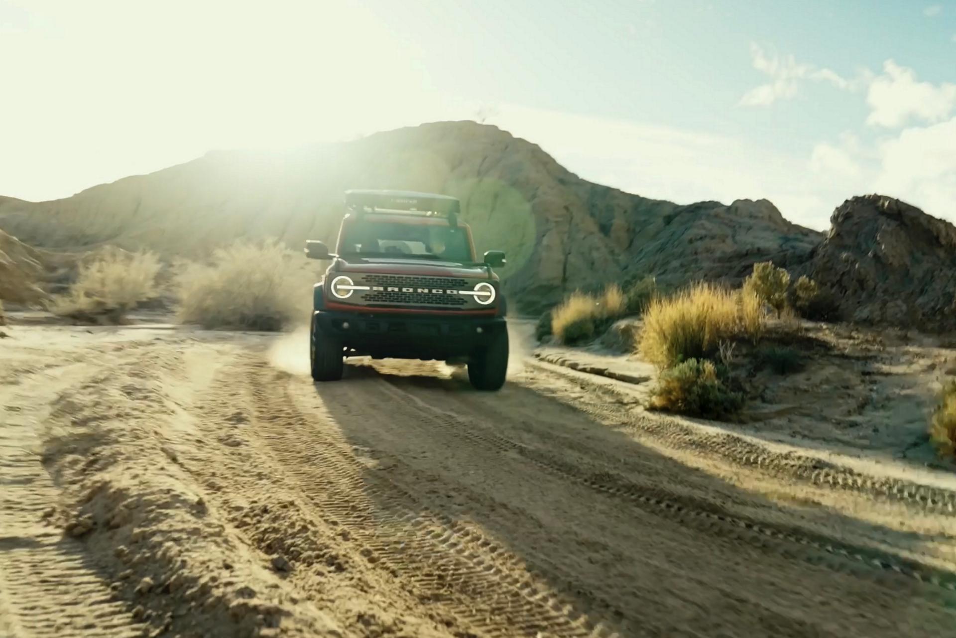 A 2026 Ford Bronco® SUV being driven on a dirt trail through a stark, dusty landscape
