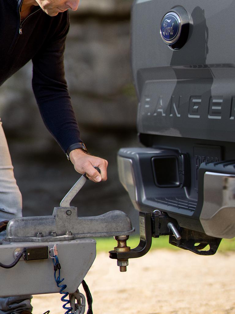 A person's hand is using the Trailer Tow Package to hitch a trailer to their 2026 Ford Ranger® XL truck