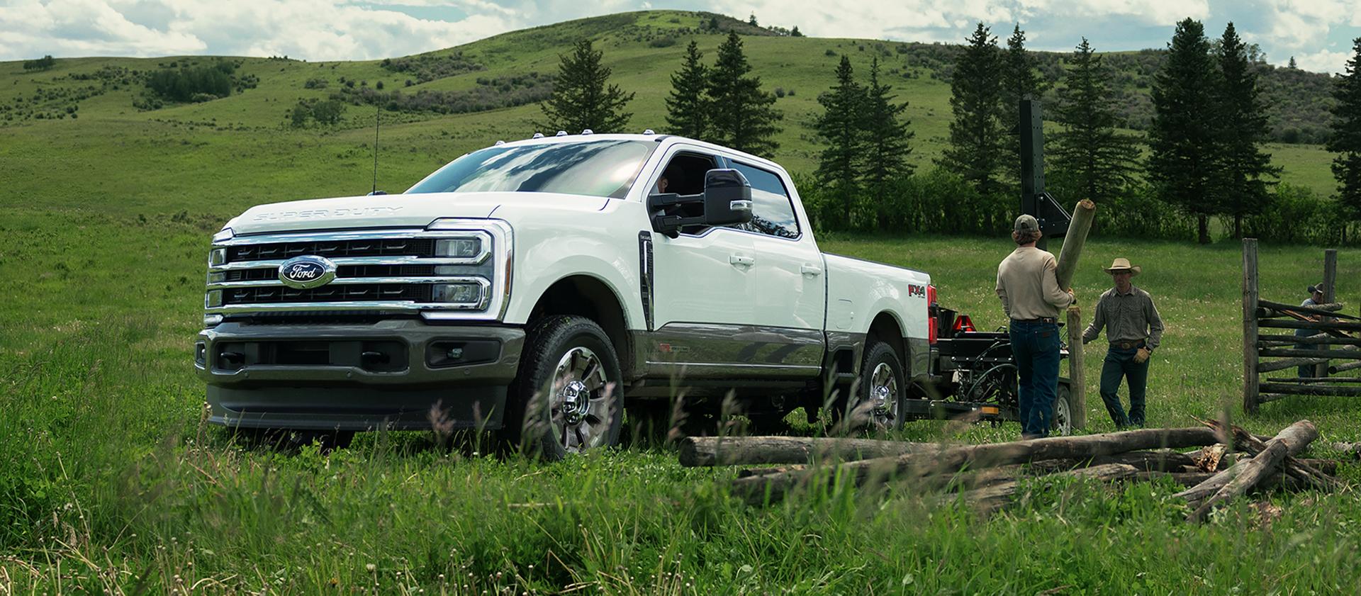 2027 Super Duty® F-350® King Ranch model towing a trailer of lumber with two workers unloading the lumber from the trailer