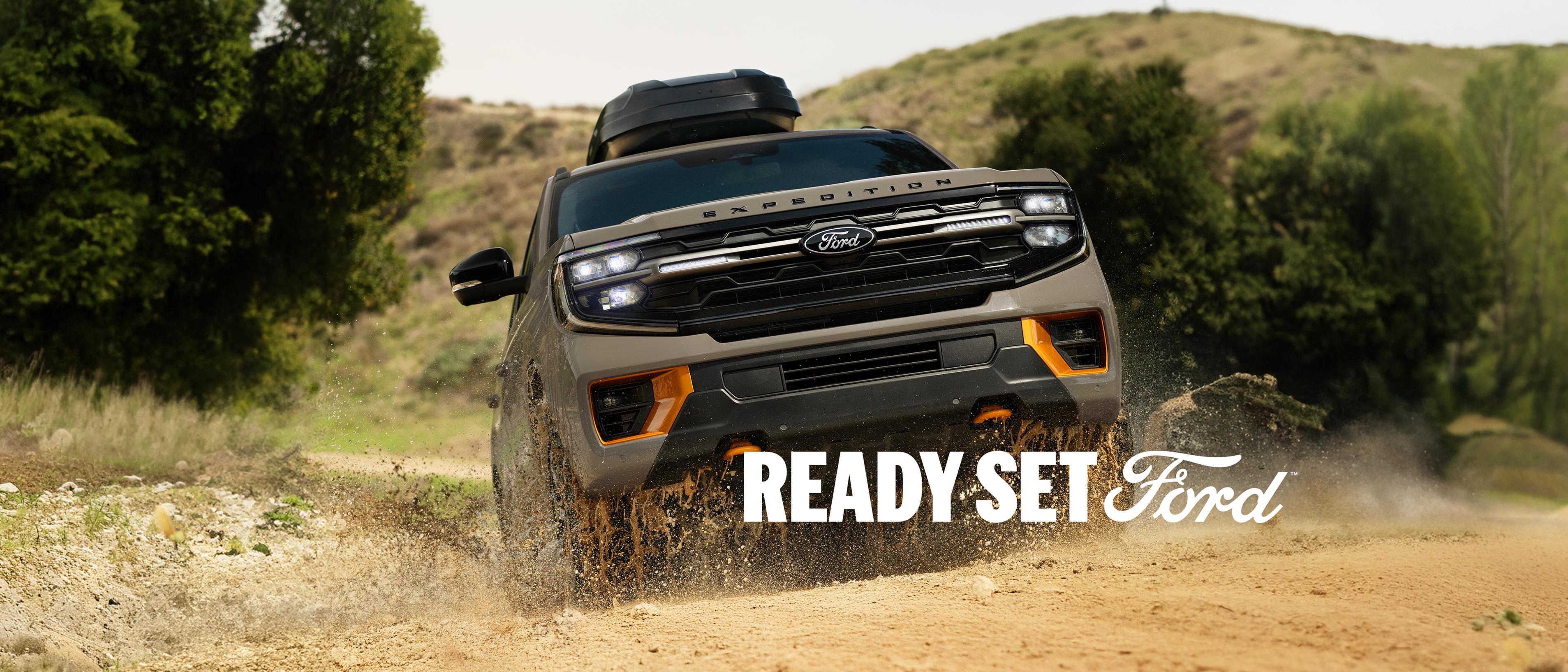 A person on a bicycle near a parked 2026 Ford Expedition® Tremor® model with available Ford accessories