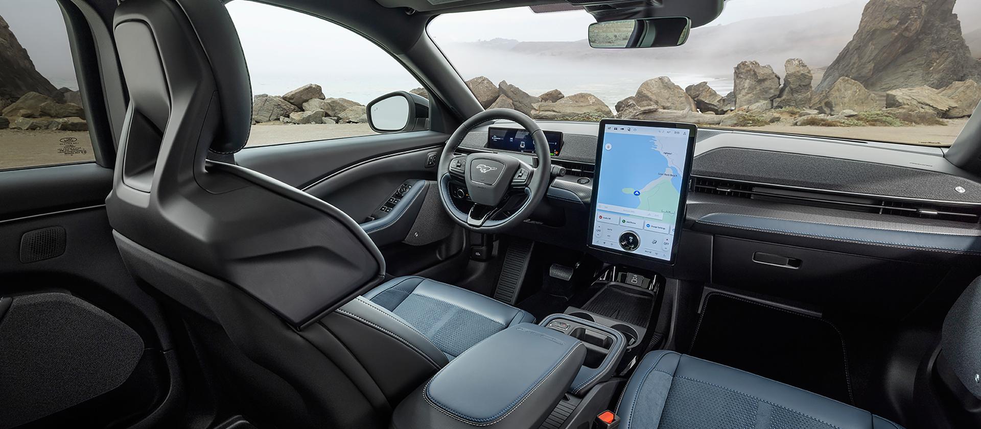 Interior of a 2026 Ford Mustang Mach-E® SUV with a view of the driver's seat, dashboard, and scenic rocky landscape