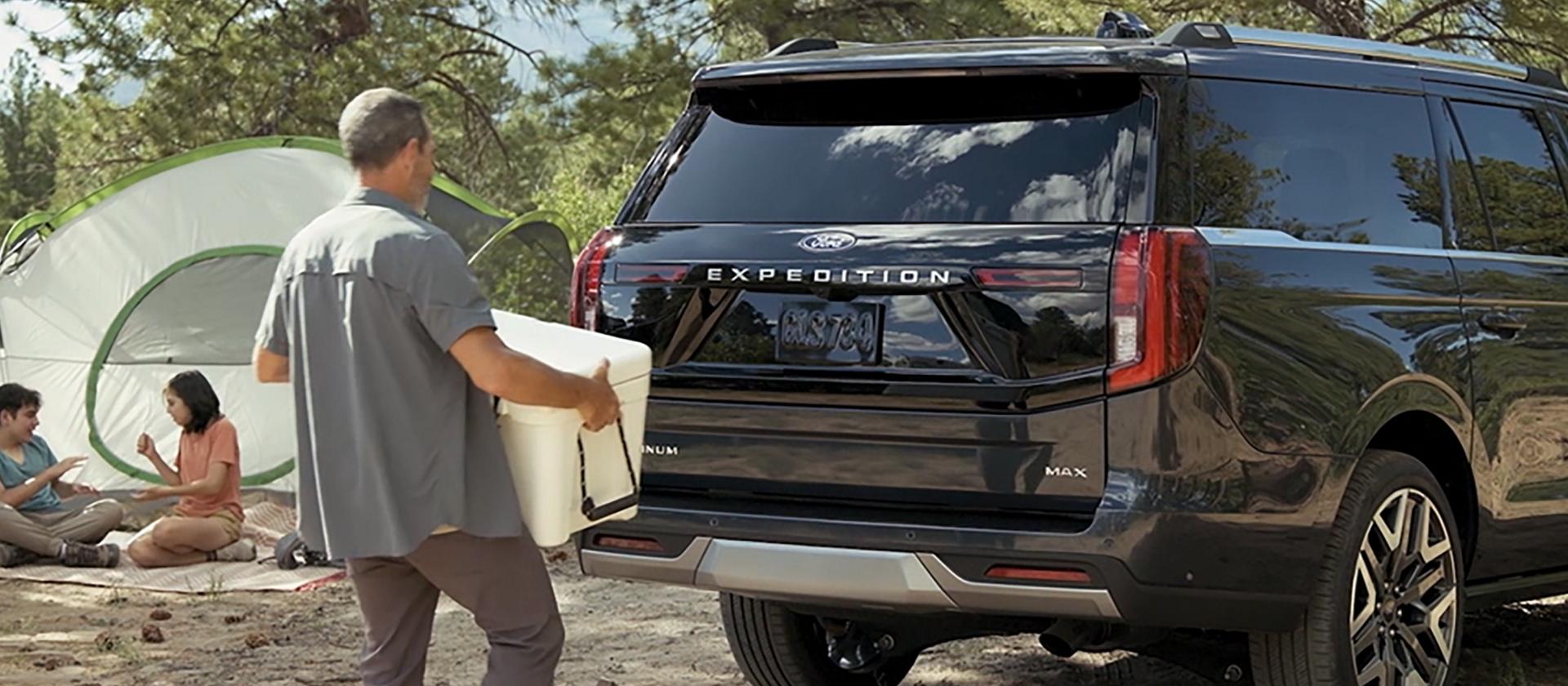 A person using the Ford Split Gate with available Open On Approach to load a cooler in a 2026 Ford Expedition® SUV