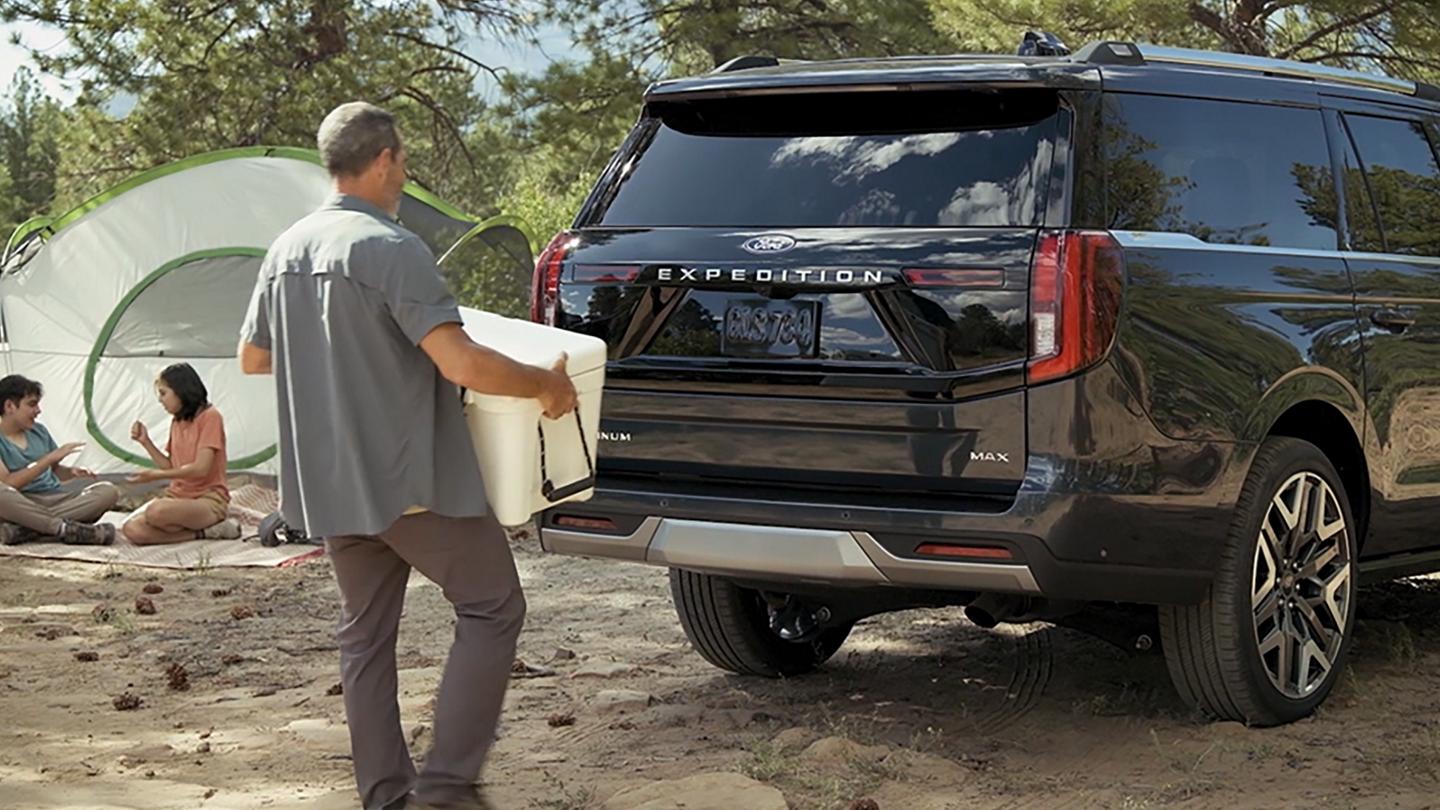 A person using the Ford Split Gate with available Open On Approach to load a cooler in a 2026 Ford Expedition® SUV